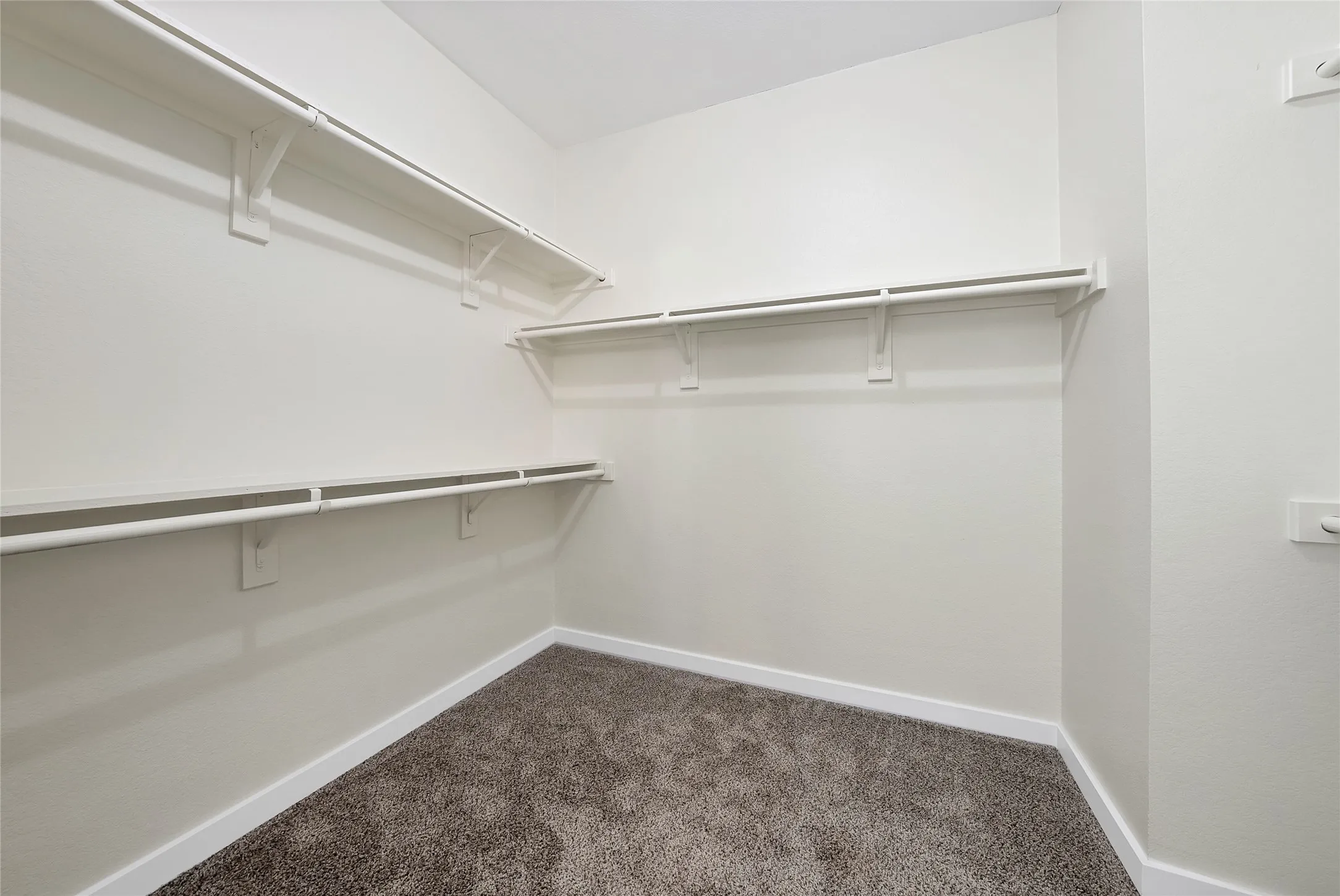 Expansive walk-in closet featuring white wall-mounted shelving and clothing rods