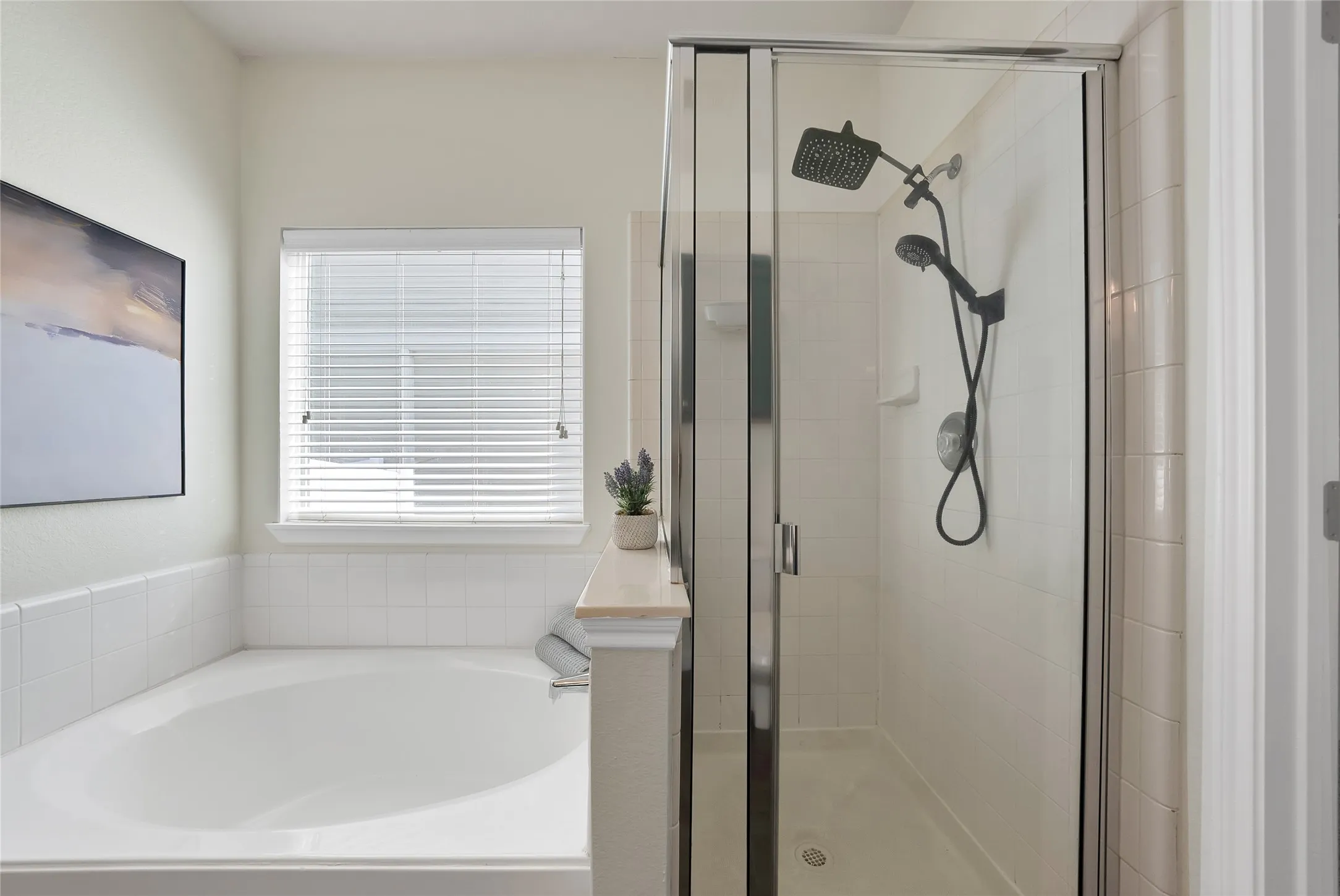 Built-in soaking tub with tile surround, separate shower enclosure with glass panels, and matte black shower fixtures