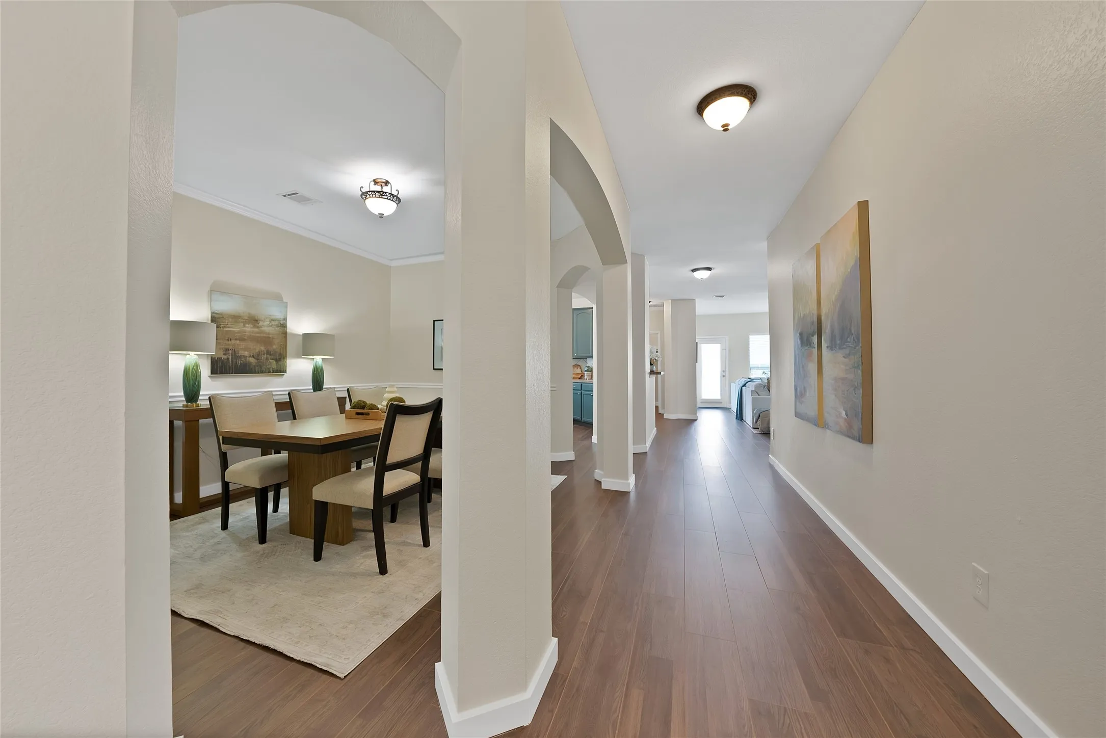 Wood-finish flooring throughout, featuring arched doorways and crown molding