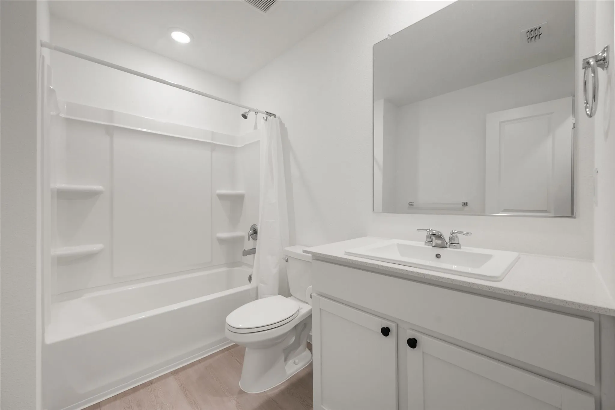 White vanity with black cabinet pulls, undermount sink, chrome faucet, and expansive mirror