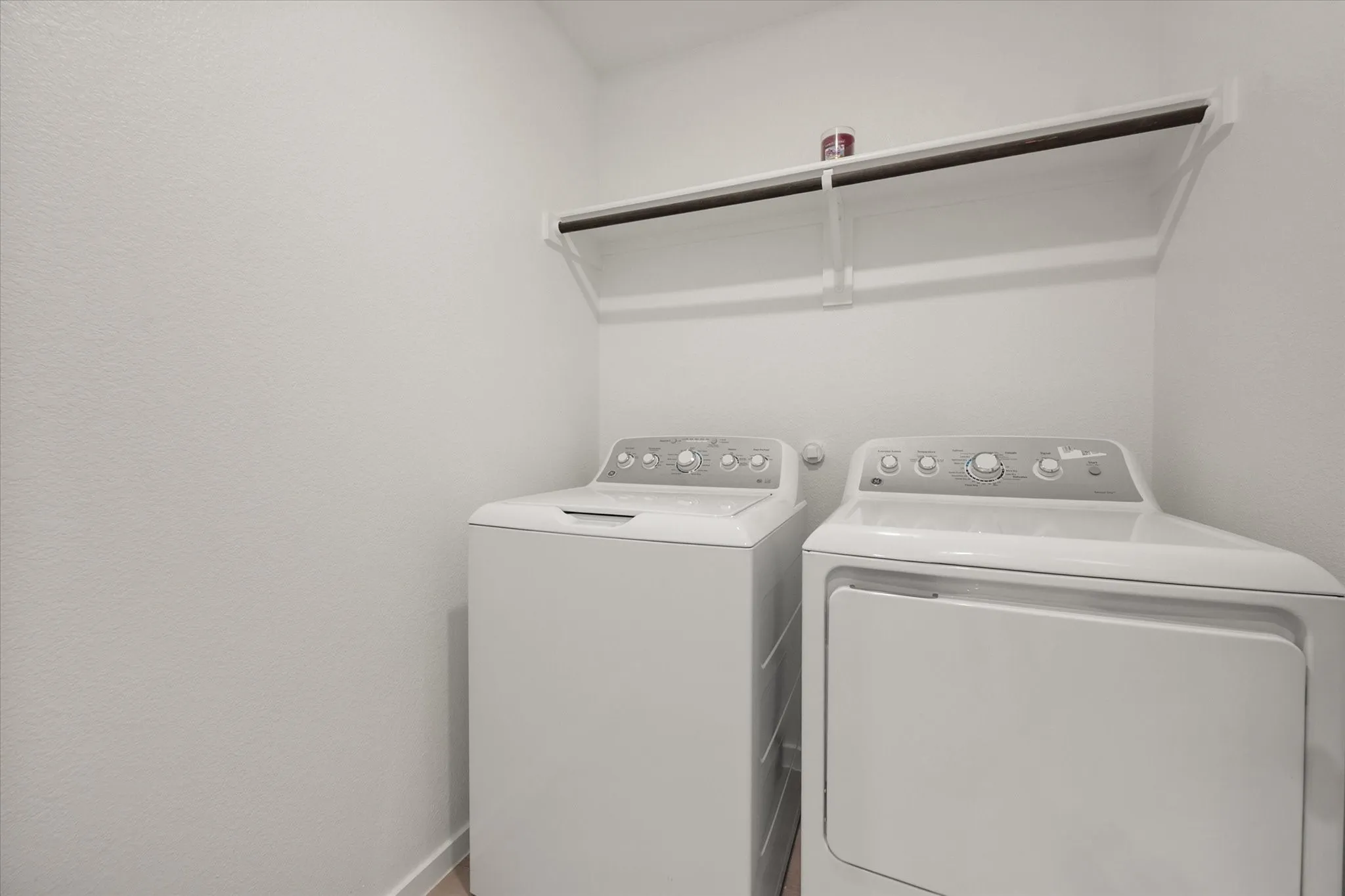 Dedicated laundry area featuring a washer and dryer, built-in shelving, and a hanging rod