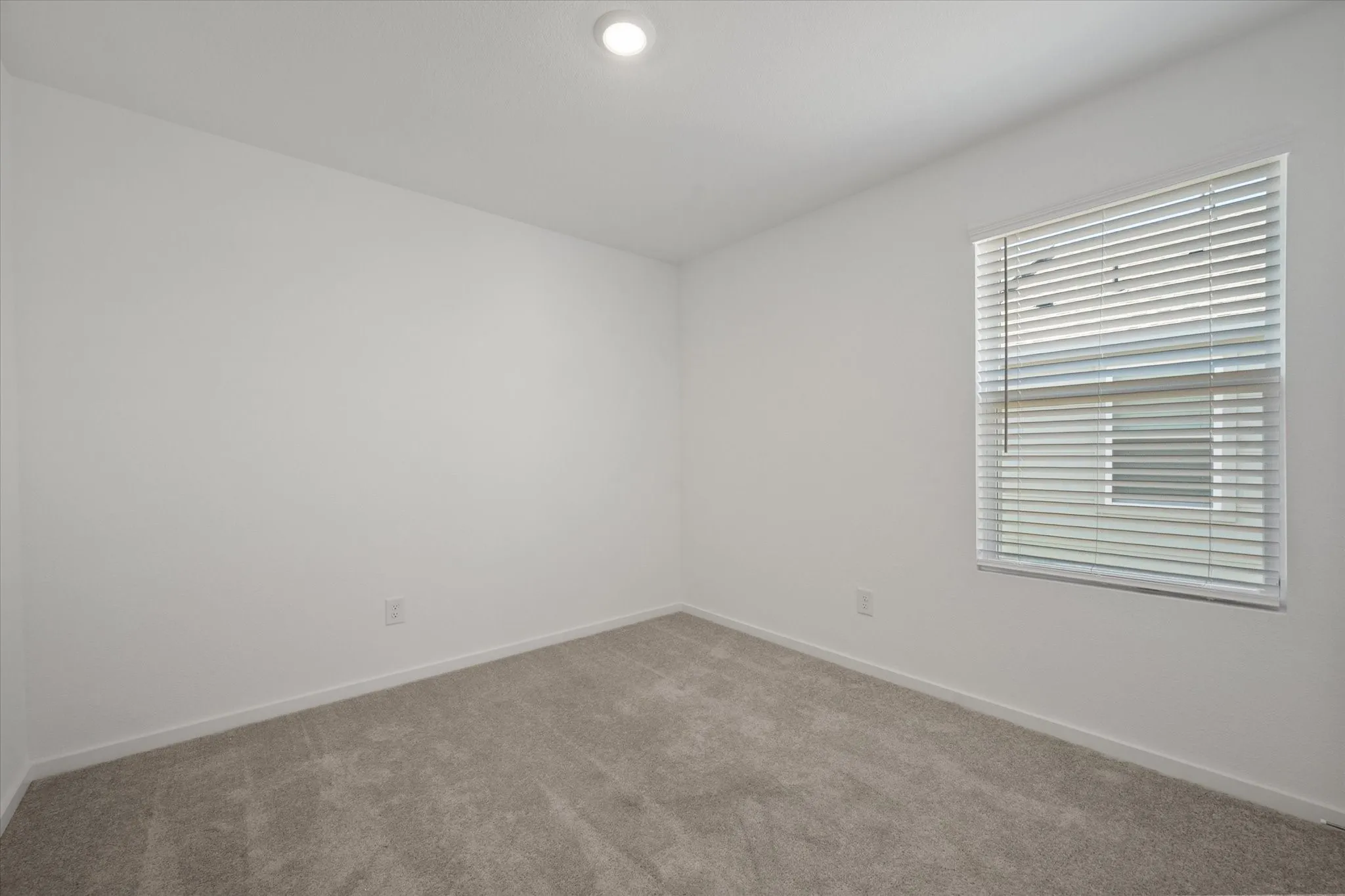 Neutral wall finishes with a window featuring horizontal blinds