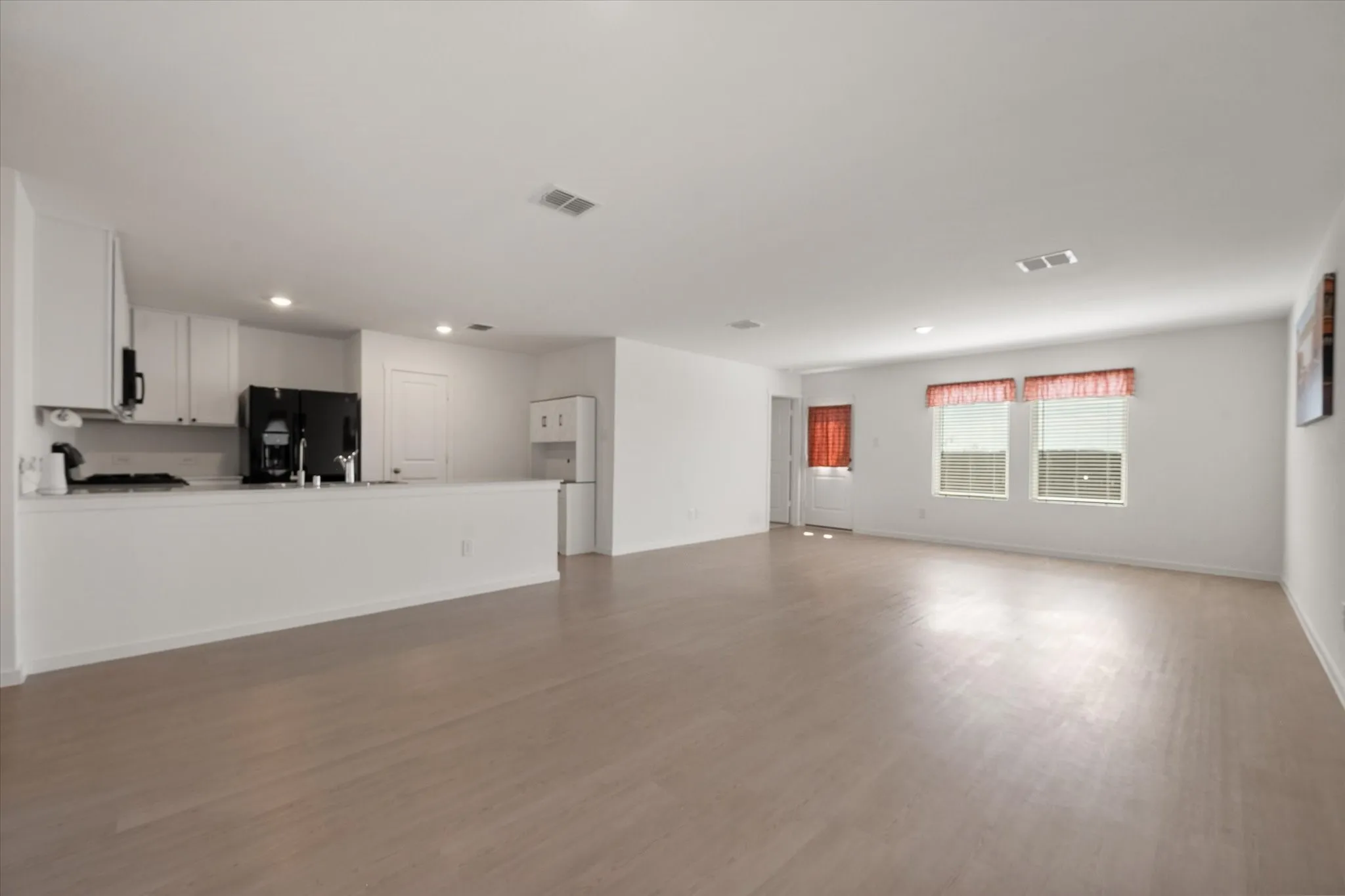 Open-concept living space with light wood-finish flooring, recessed lighting, and white walls