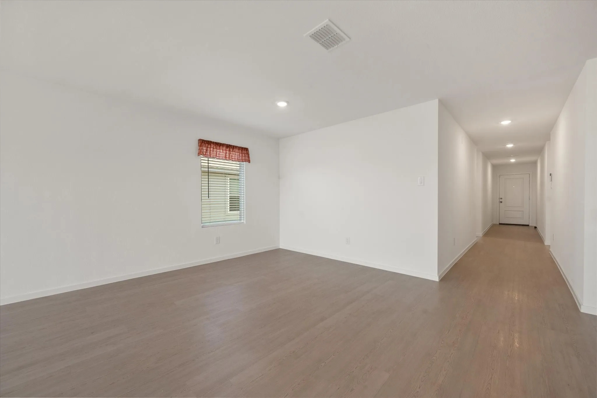 Expansive room featuring wood-finish flooring, recessed lighting, and a window with horizontal blinds