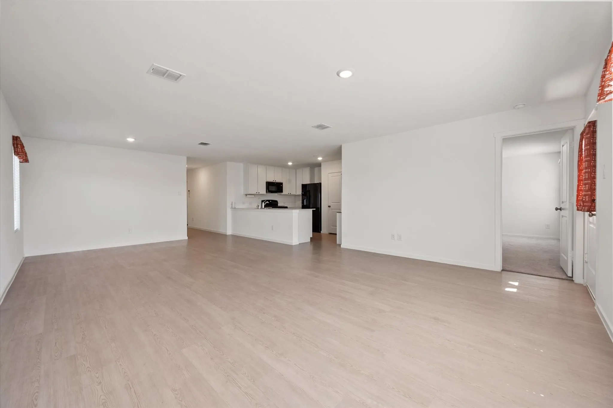 Open-concept layout with wood-finish flooring, recessed lighting, and white walls