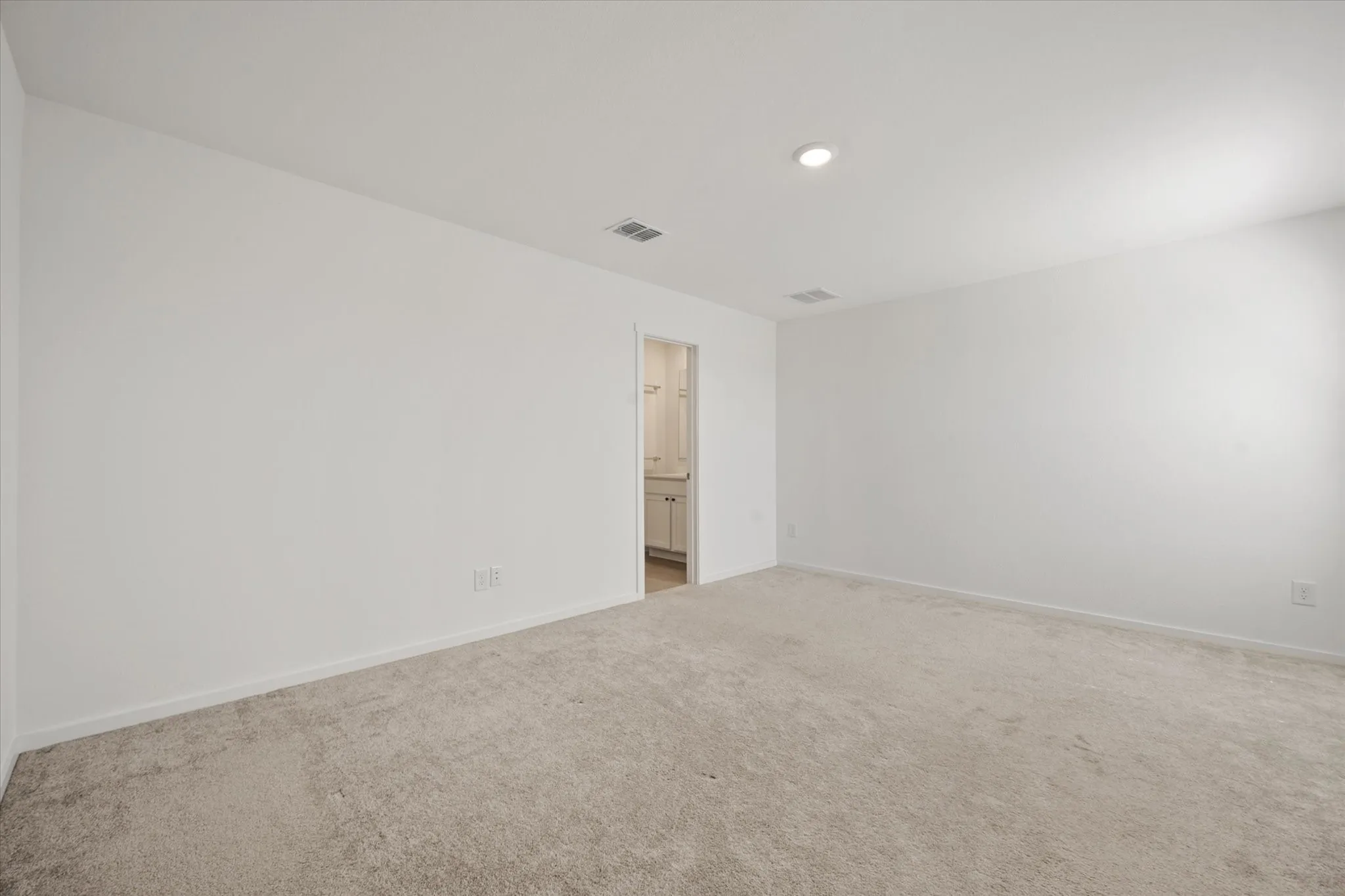 Expansive room with neutral carpeting and white wall finishes