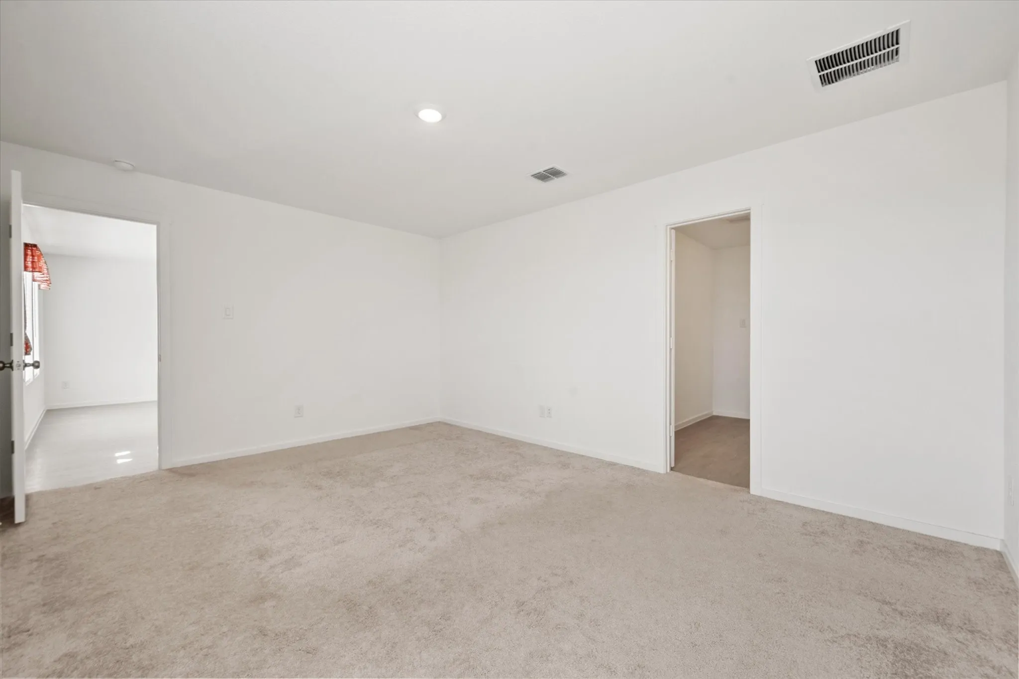 Neutral-toned carpeting with white walls and a recessed ceiling light