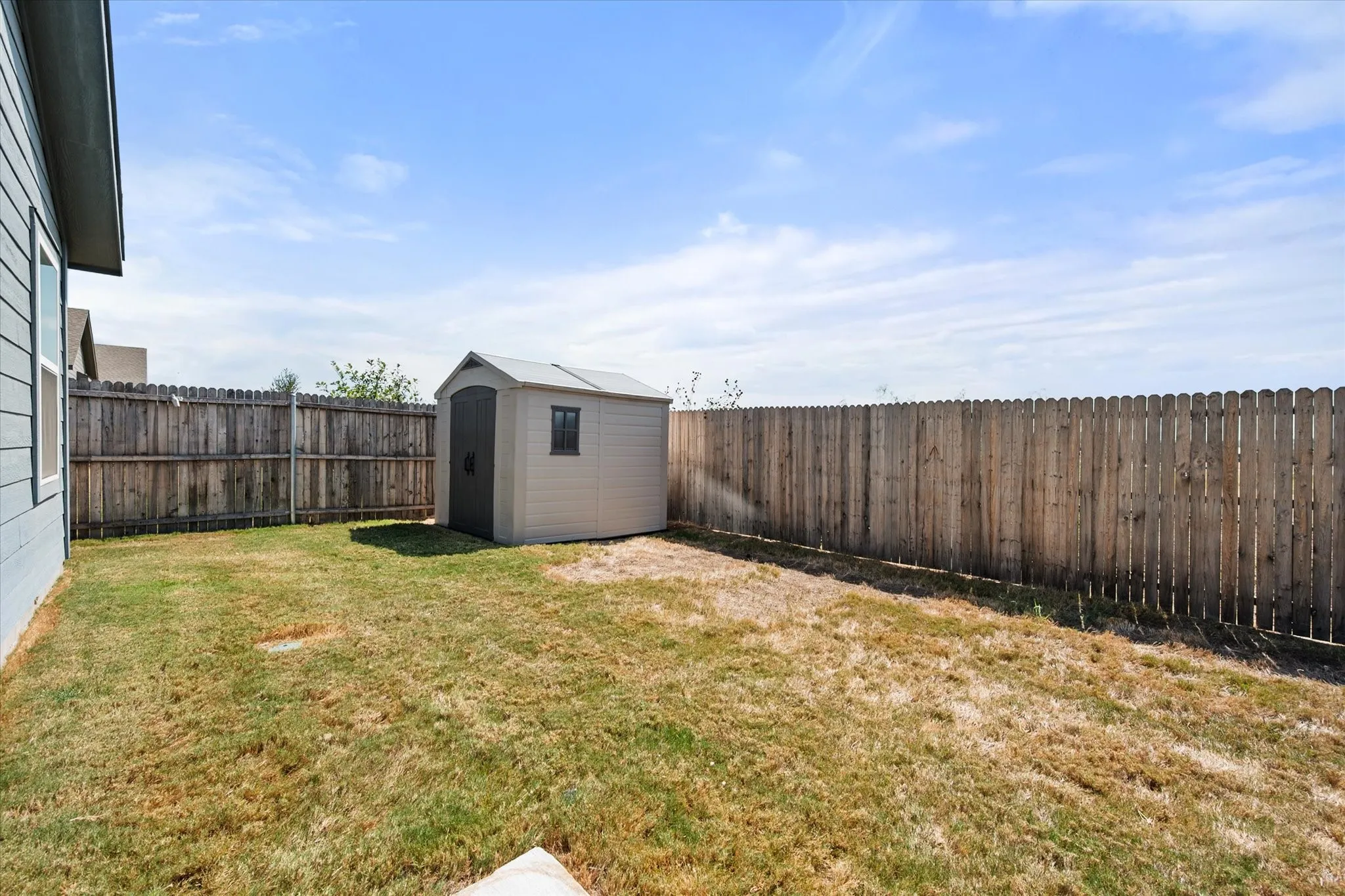 Fenced backyard with a storage shed