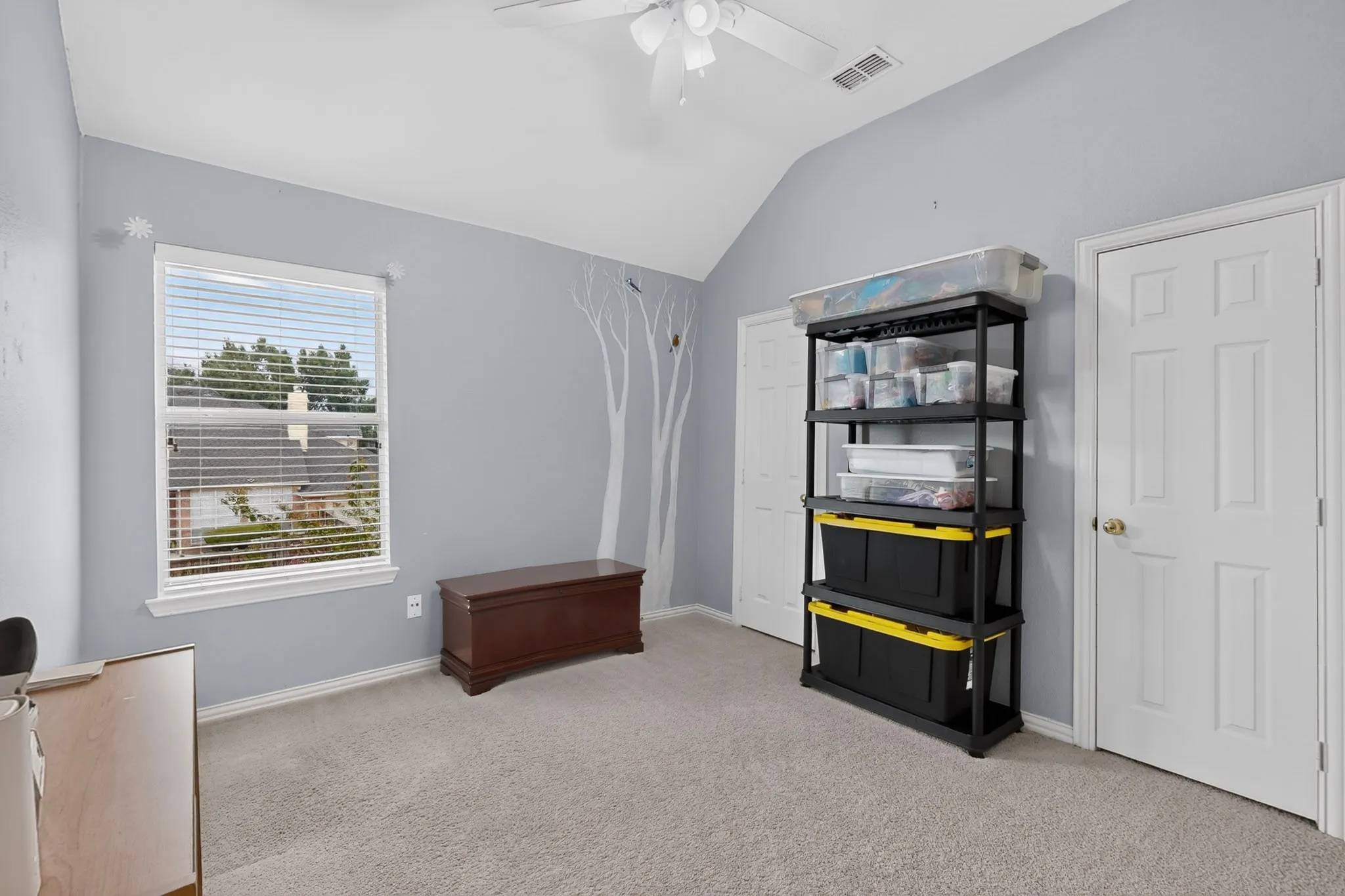 Vaulted ceiling, ceiling fan, natural light, gray wall color, light-toned carpeting