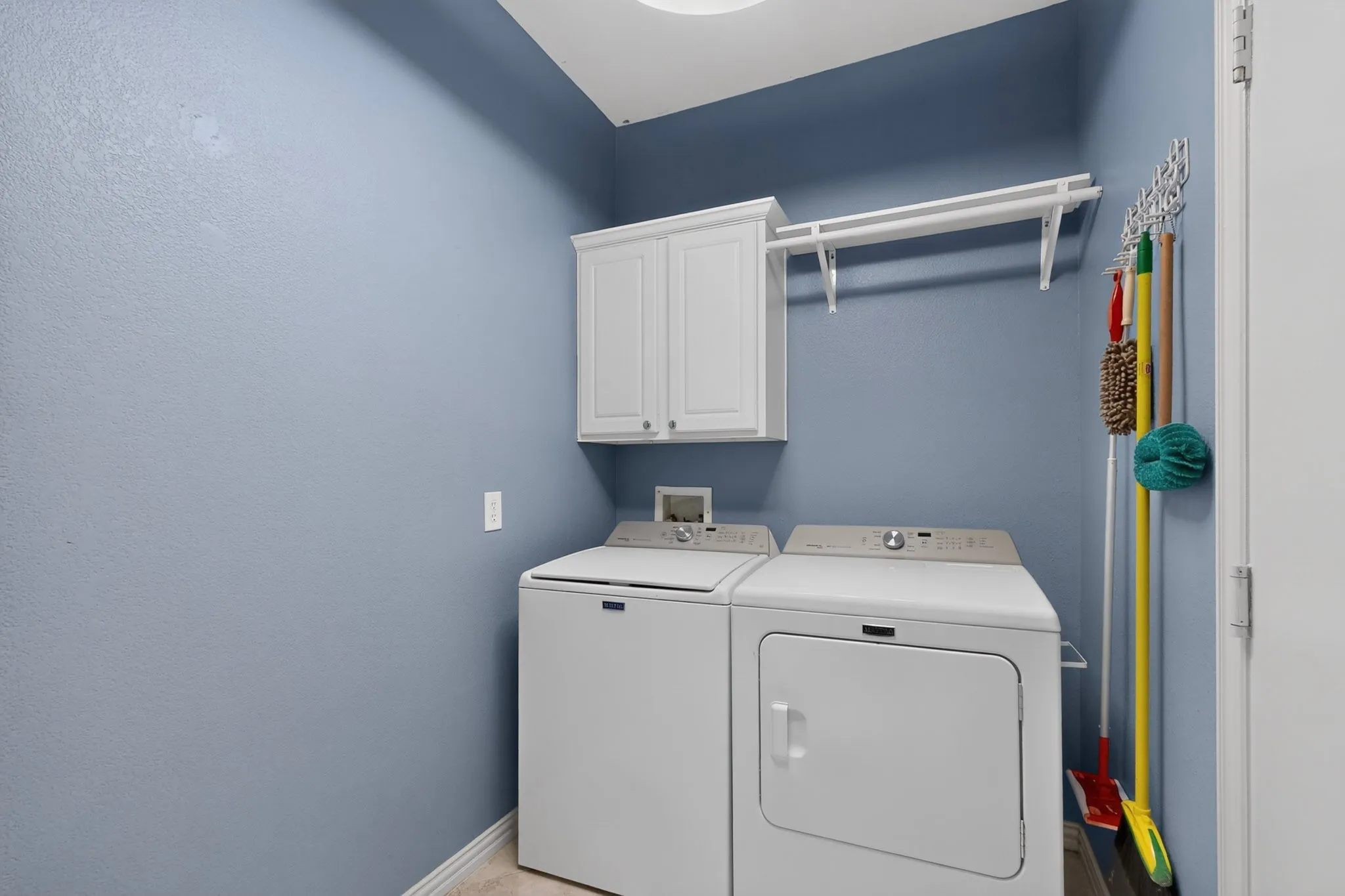 White cabinetry with silver hardware, and an overhead storage shelf