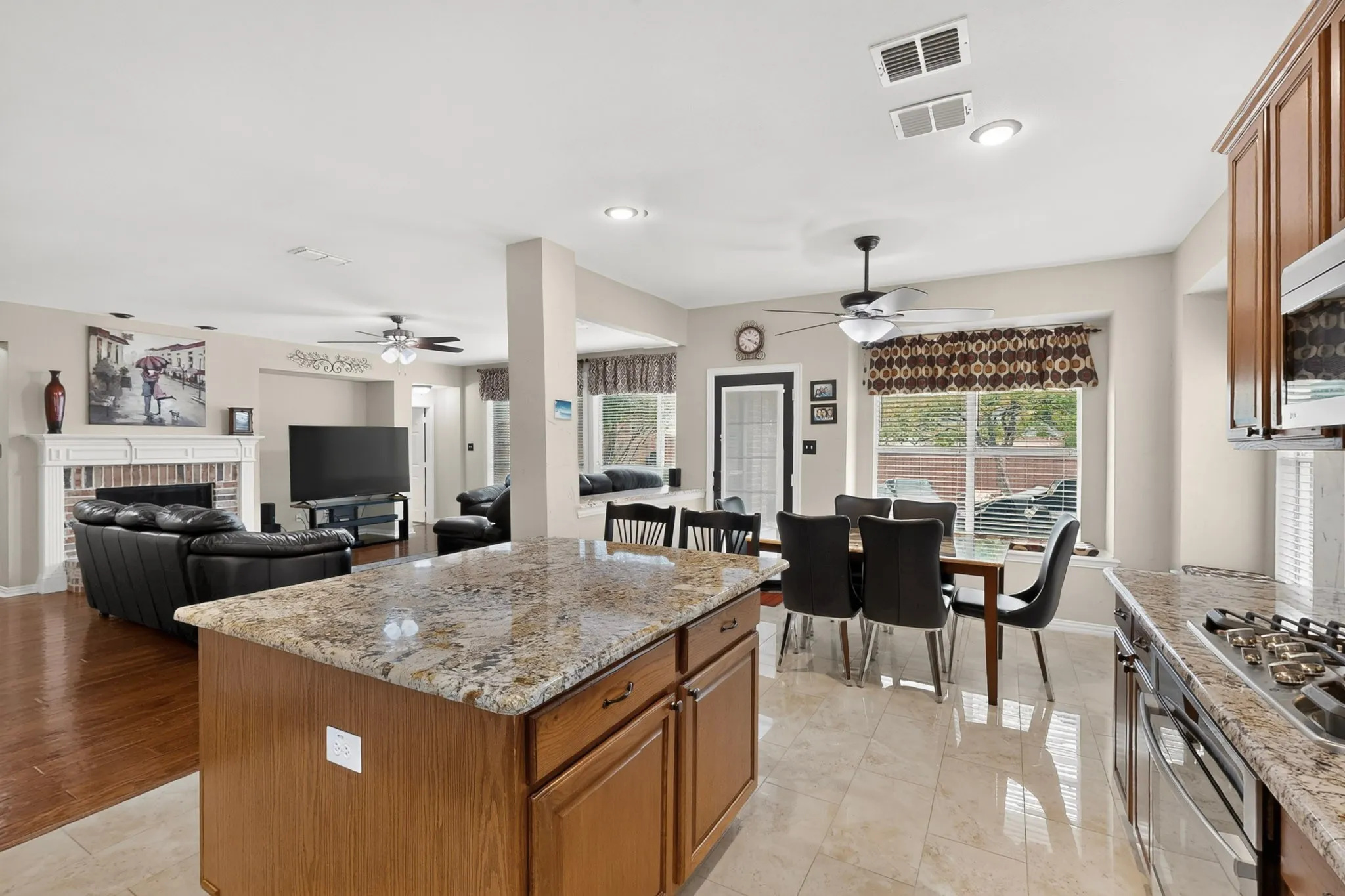 Kitchen island with granite countertop, wood-finish cabinetry, and recessed lighting