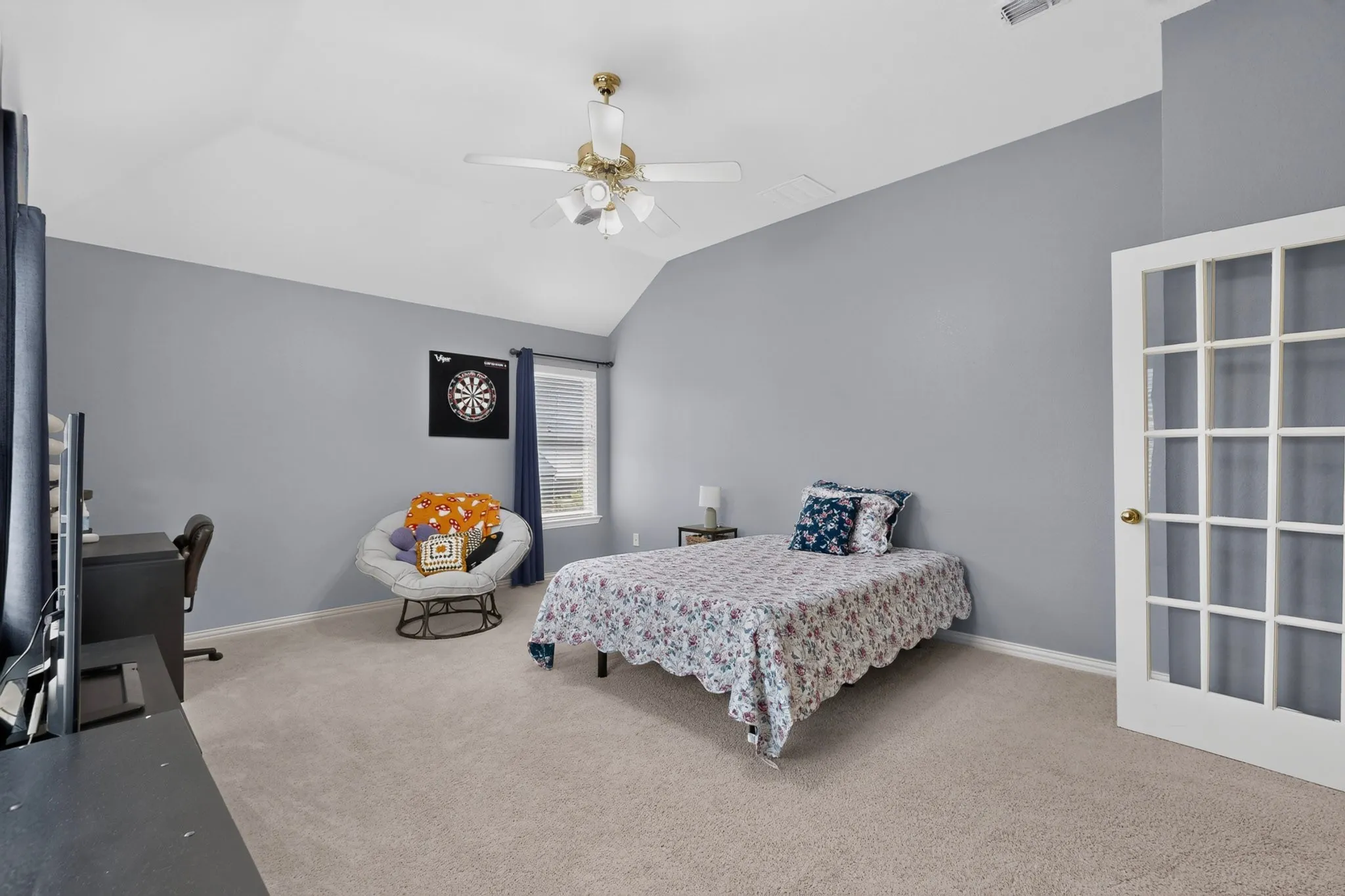 Vaulted ceiling with a ceiling fan, carpeted flooring, window with blinds, and a French pane door