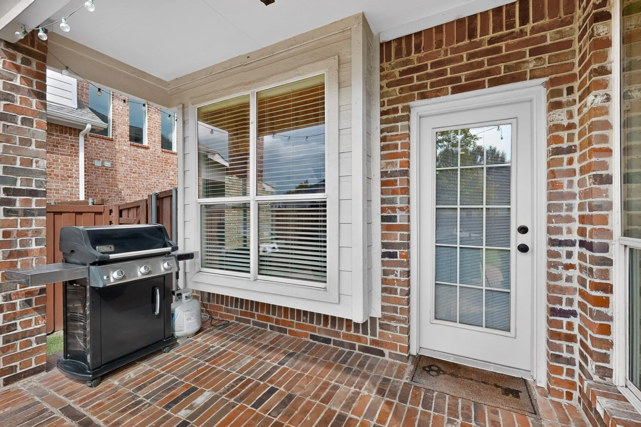 Covered brick patio featuring a multi-tone brick floor and brick exterior walls