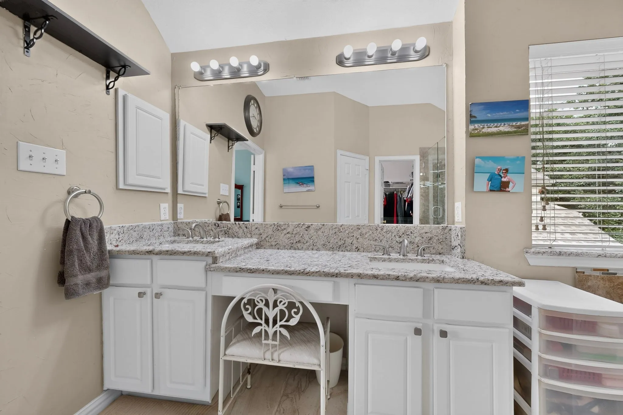 Dual sink vanity with light-colored countertops, white cabinetry, and an integrated makeup vanity