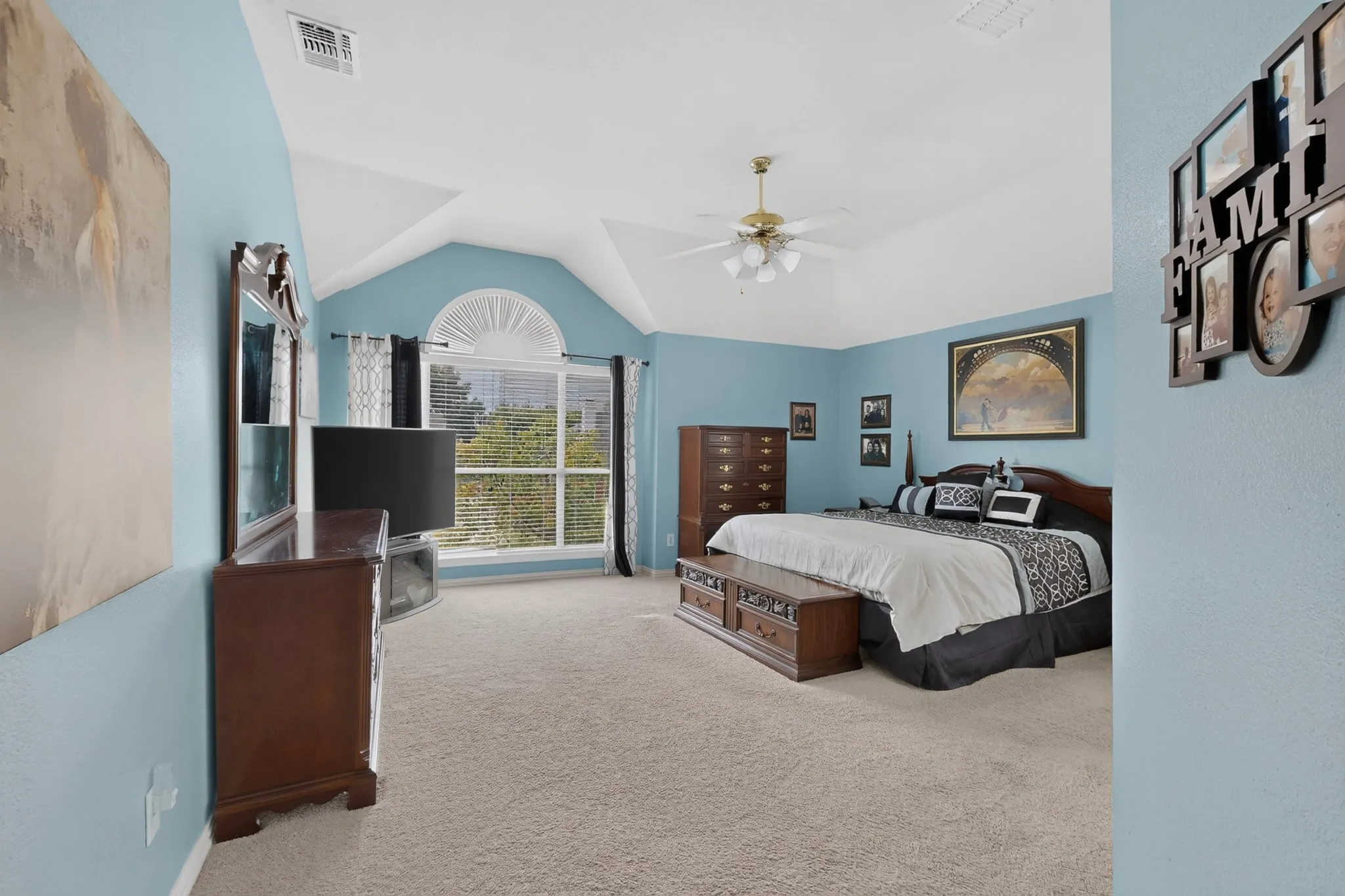 Spacious room featuring vaulted ceilings, a large arched window with blinds, and neutral carpet flooring