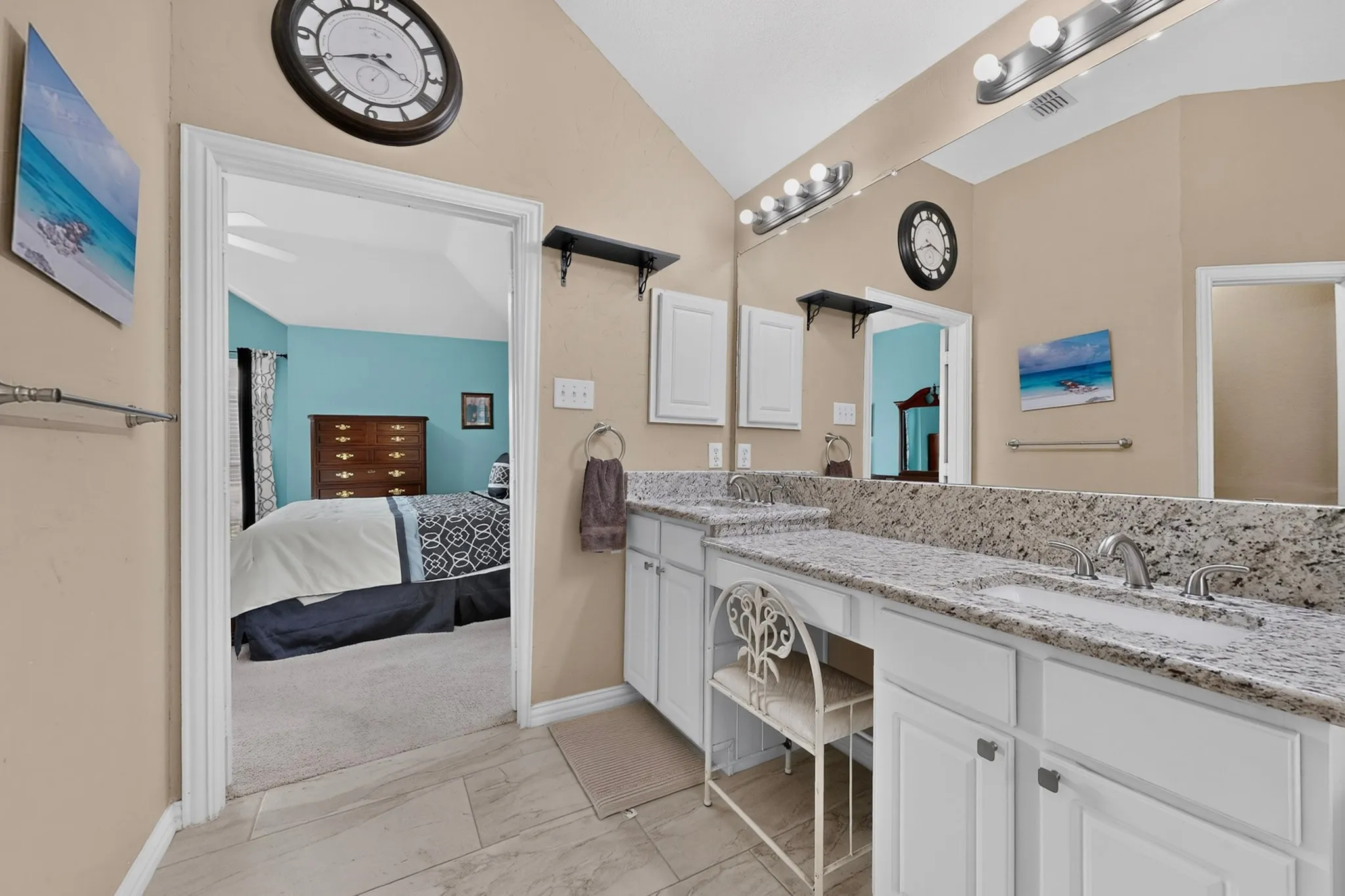 Dual vanity with stone-look countertops, integrated sinks, white cabinetry, and wall-mounted light fixtures