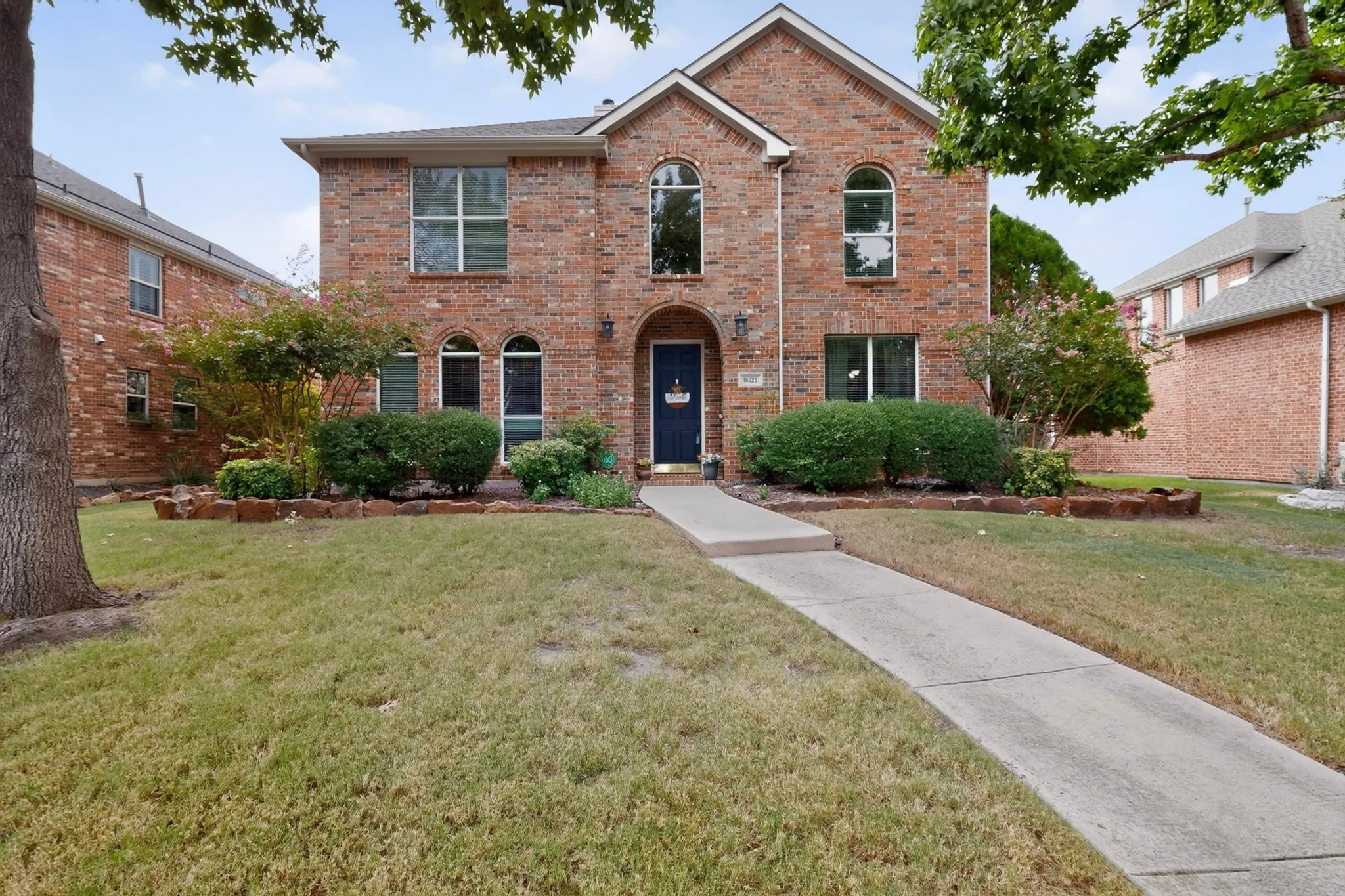 Two-story brick exterior with an arched entryway, multiple arched windows, and a paved walkway