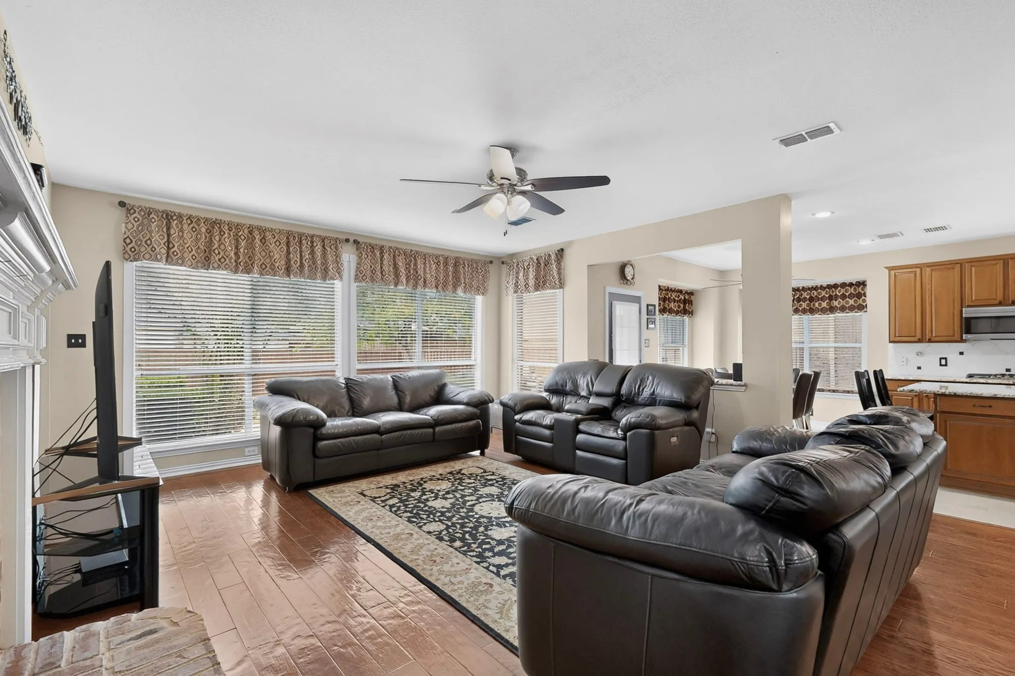 Wood-finish flooring throughout, ceiling fan with integrated lighting, recessed lighting, and a kitchen with wood cabinetry