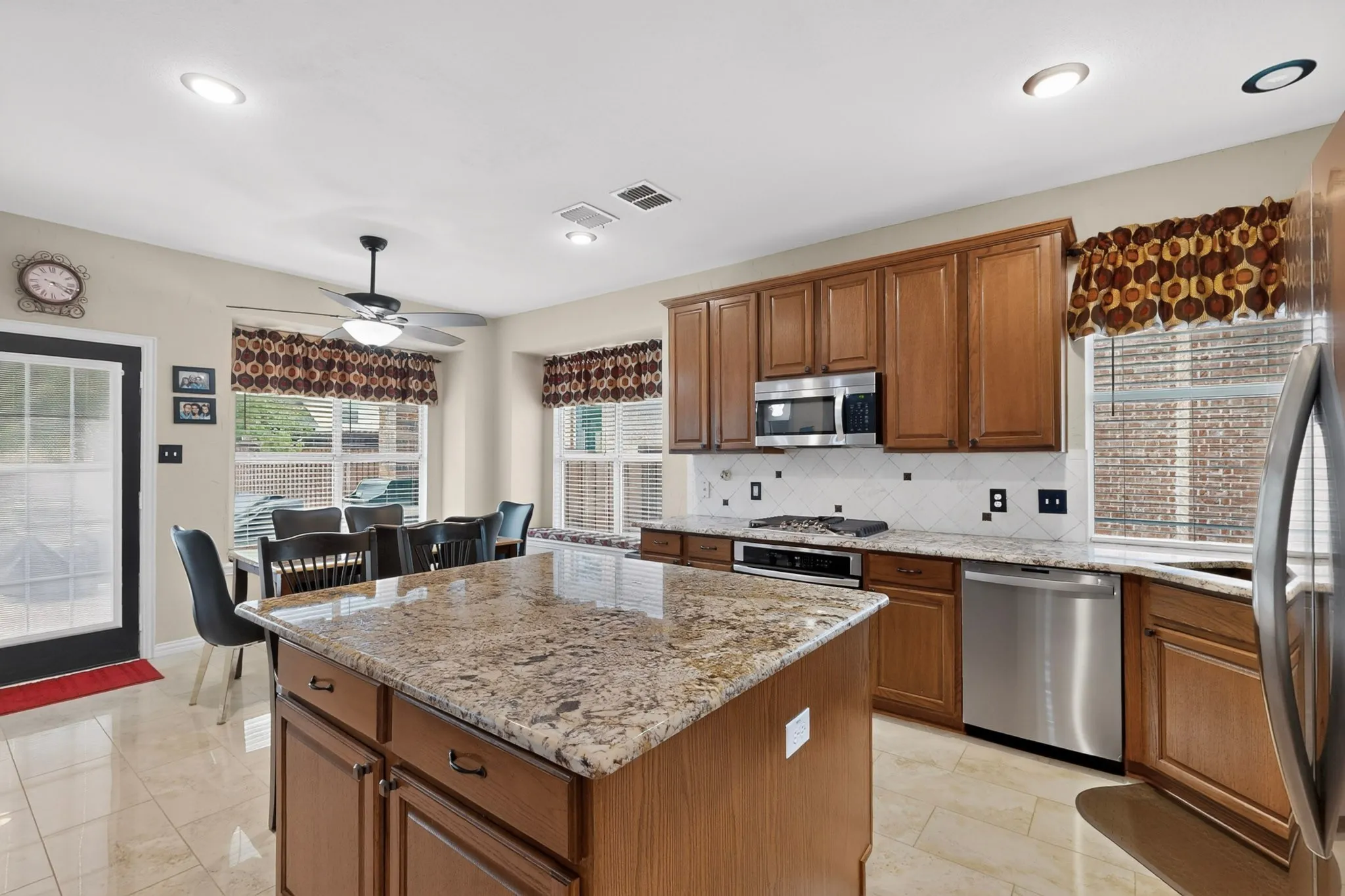 Kitchen featuring a large island with stone countertops, stainless steel appliances, ceramic tile flooring, and wood cabinetry