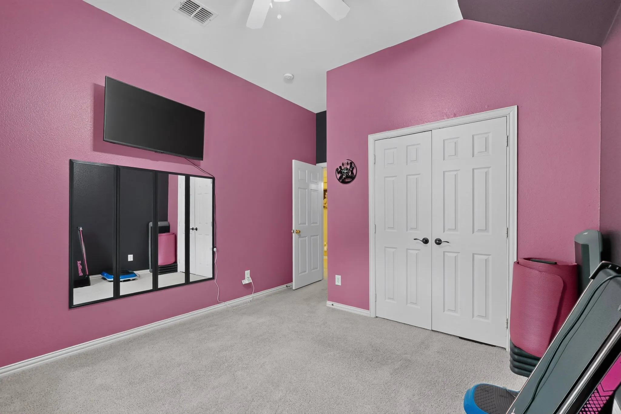 Vaulted ceiling with a ceiling fan, light-colored carpet, and bi-fold doors