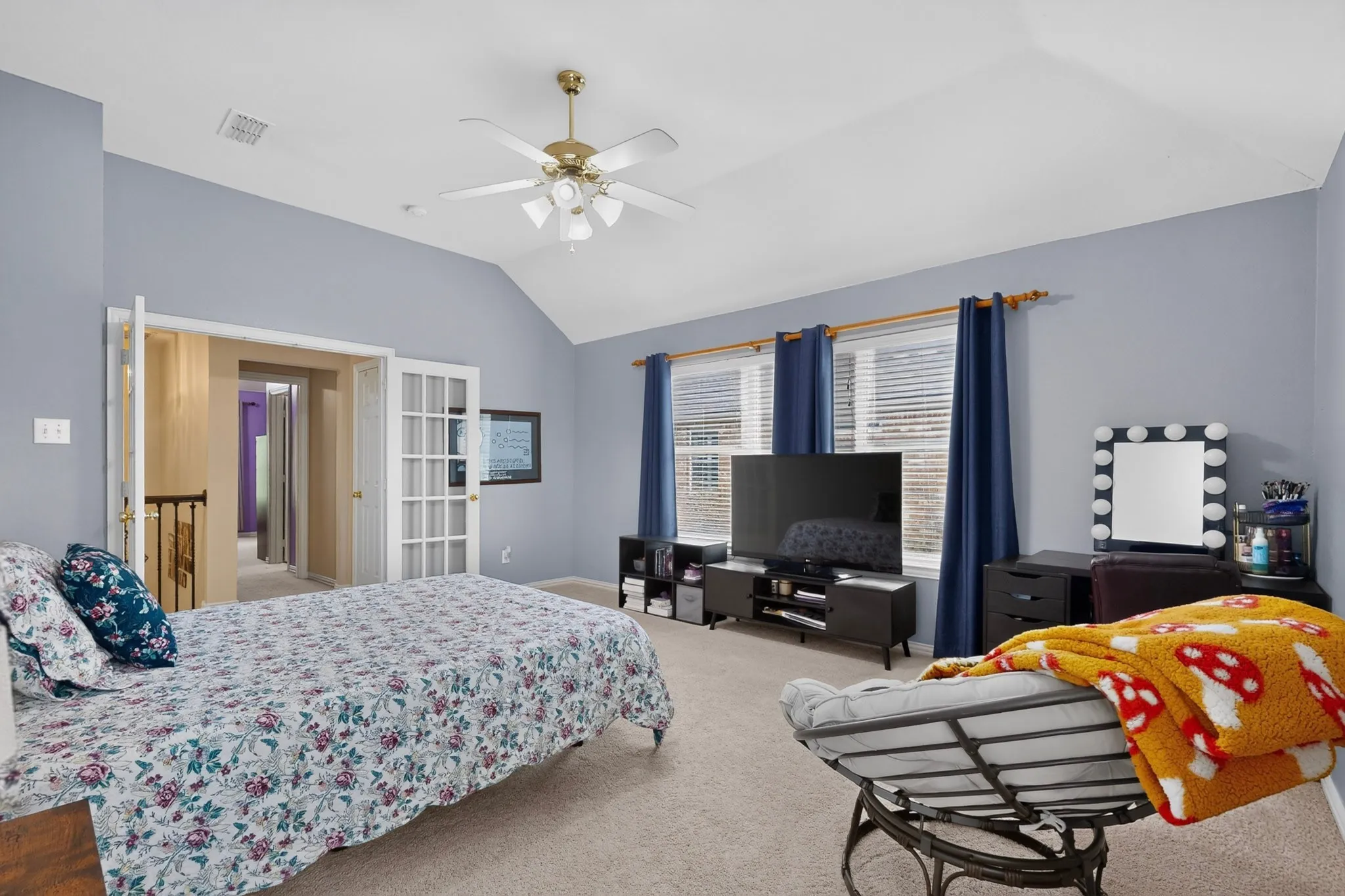 Vaulted ceiling with an attached ceiling fan, dual windows, and carpet flooring