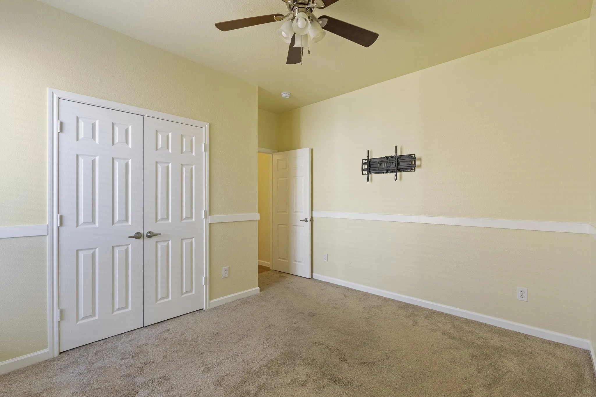 Neutral wall color, carpeted flooring, white six-panel doors, ceiling fan, and chair rail molding