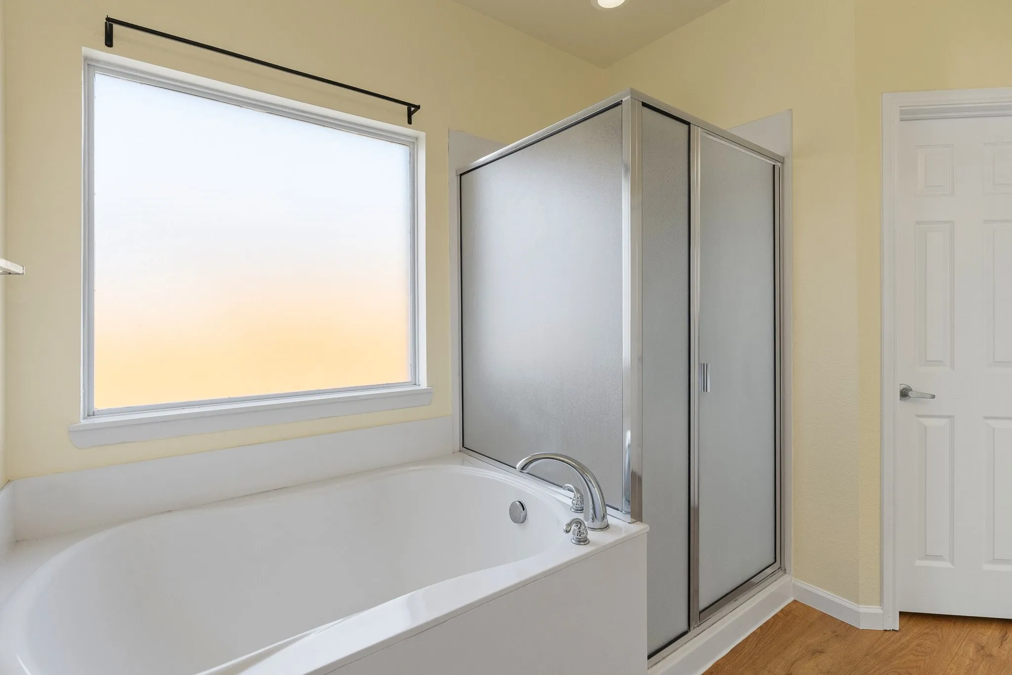 Built-in soaking tub with deck-mounted faucet, privacy window, and an adjacent enclosed shower