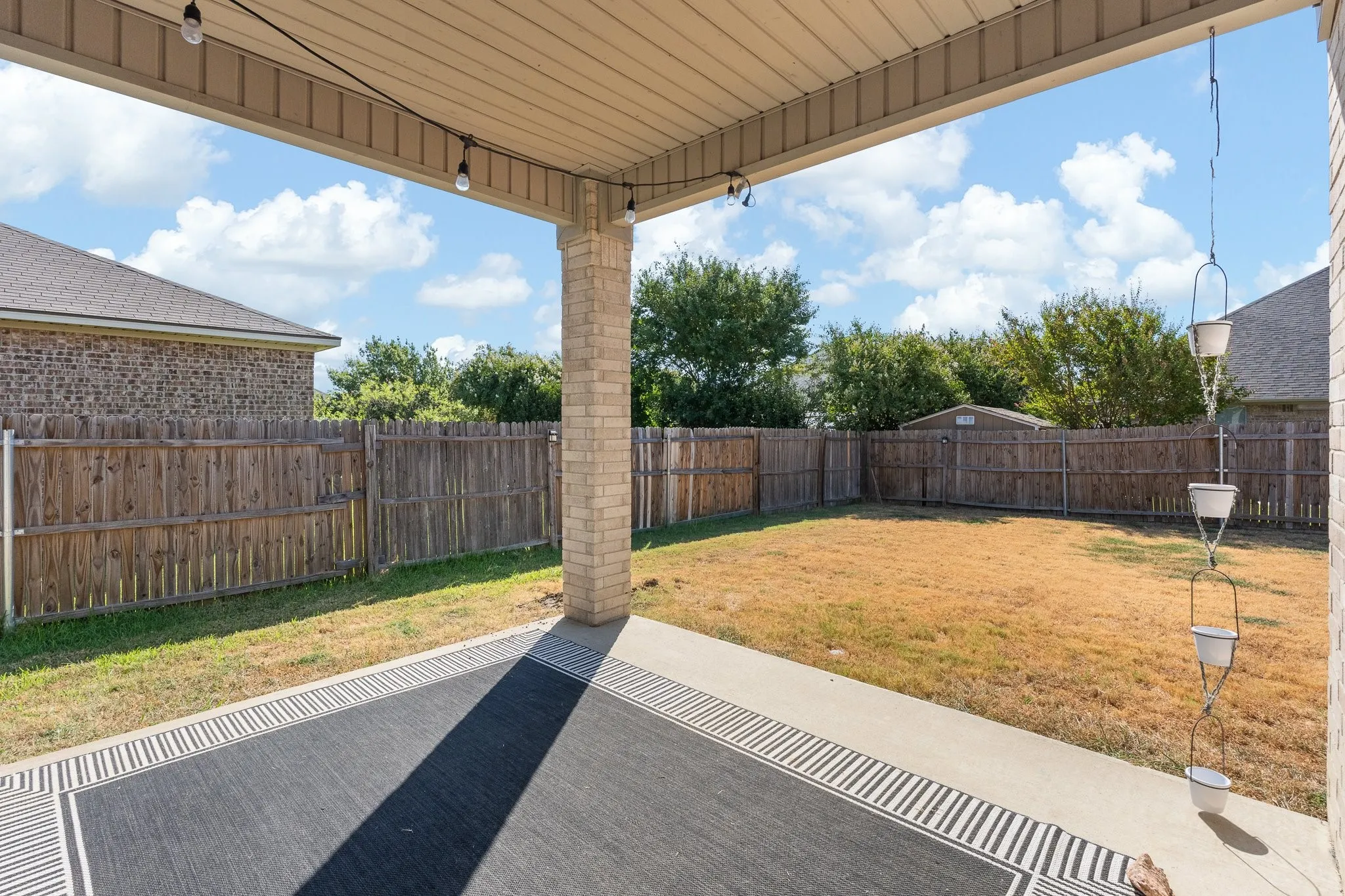 Covered patio with string lighting and a brick support column
