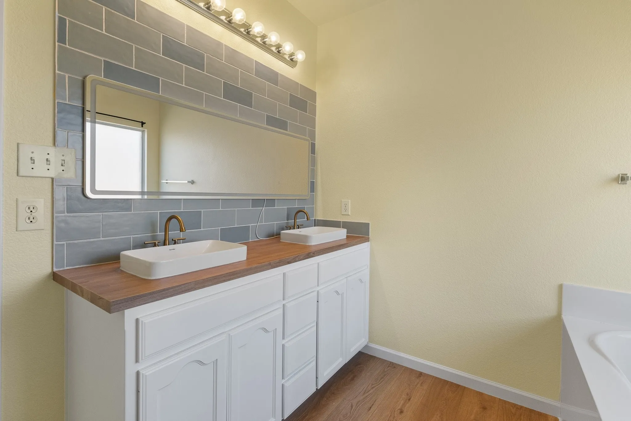 Double vanity with wood-finish countertop, dual vessel sinks, and bronze-finish fixtures