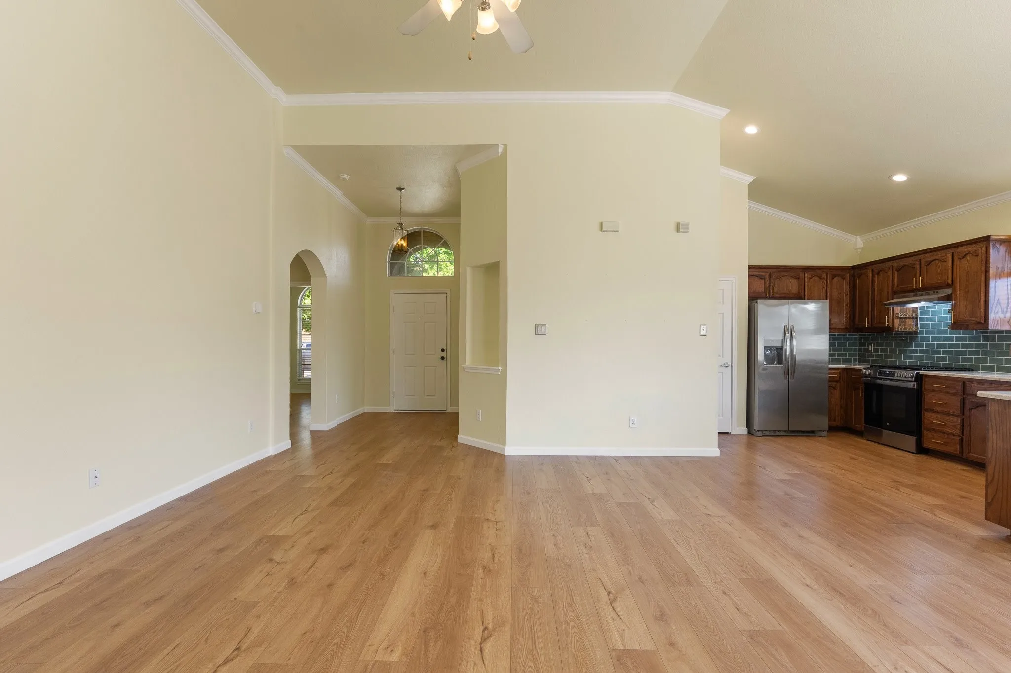 Wood-finish flooring throughout, stainless steel refrigerator, stainless steel range, archway entry, and crown molding accents