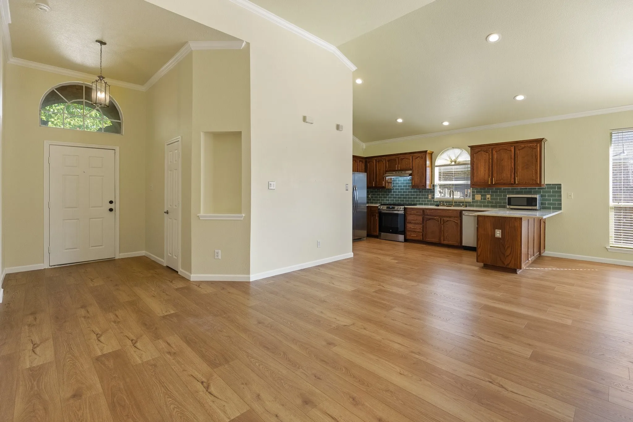 Vaulted entry with arched transom window, wood-finish flooring, and built-in niche
