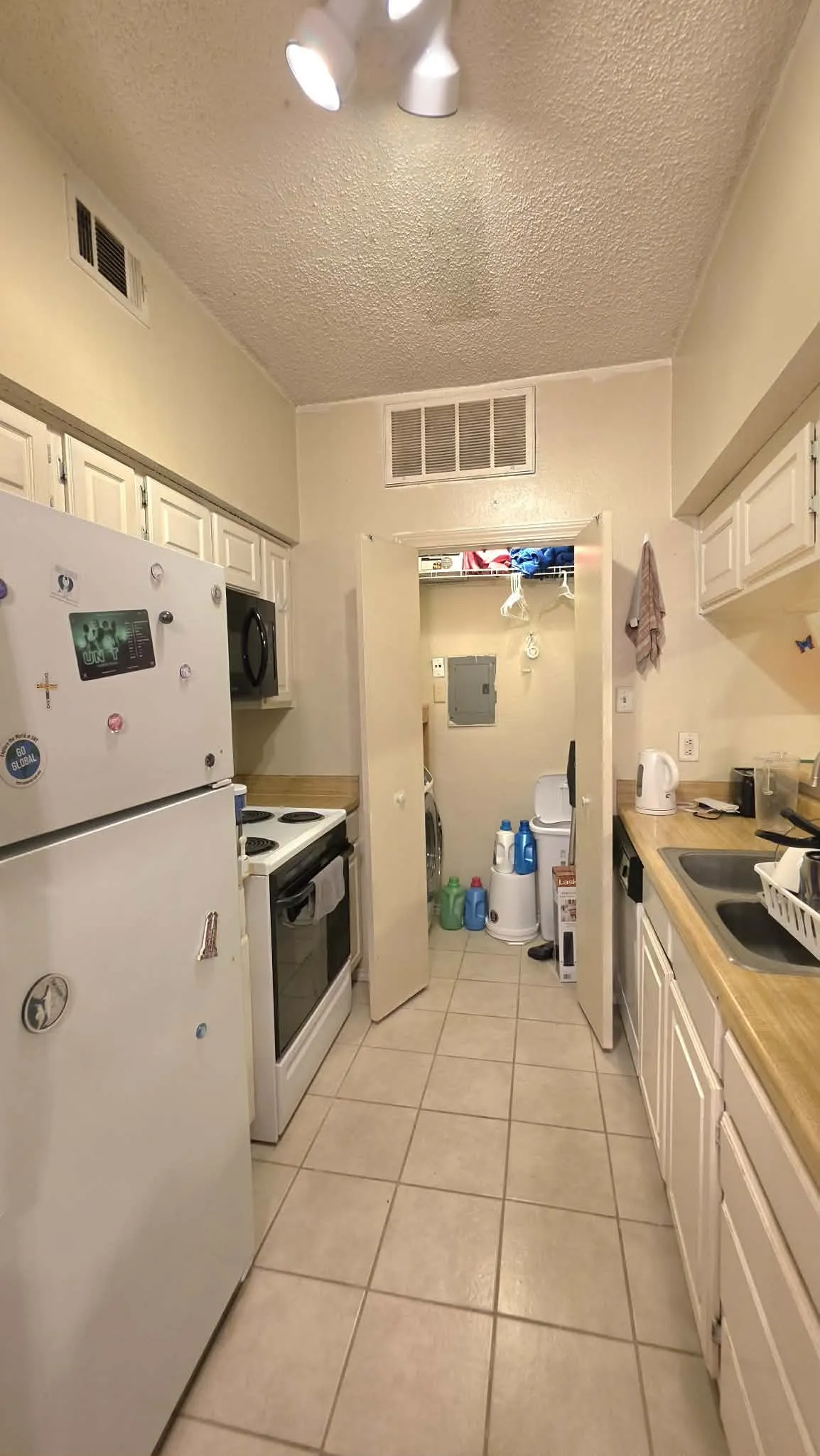 Galley kitchen featuring white cabinetry, light wood-finish countertops, and a tile floor