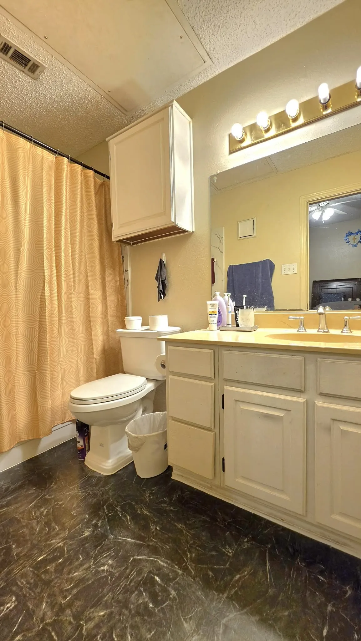 Vanity with integrated sink, white cabinetry, overhead storage, and vanity lighting
