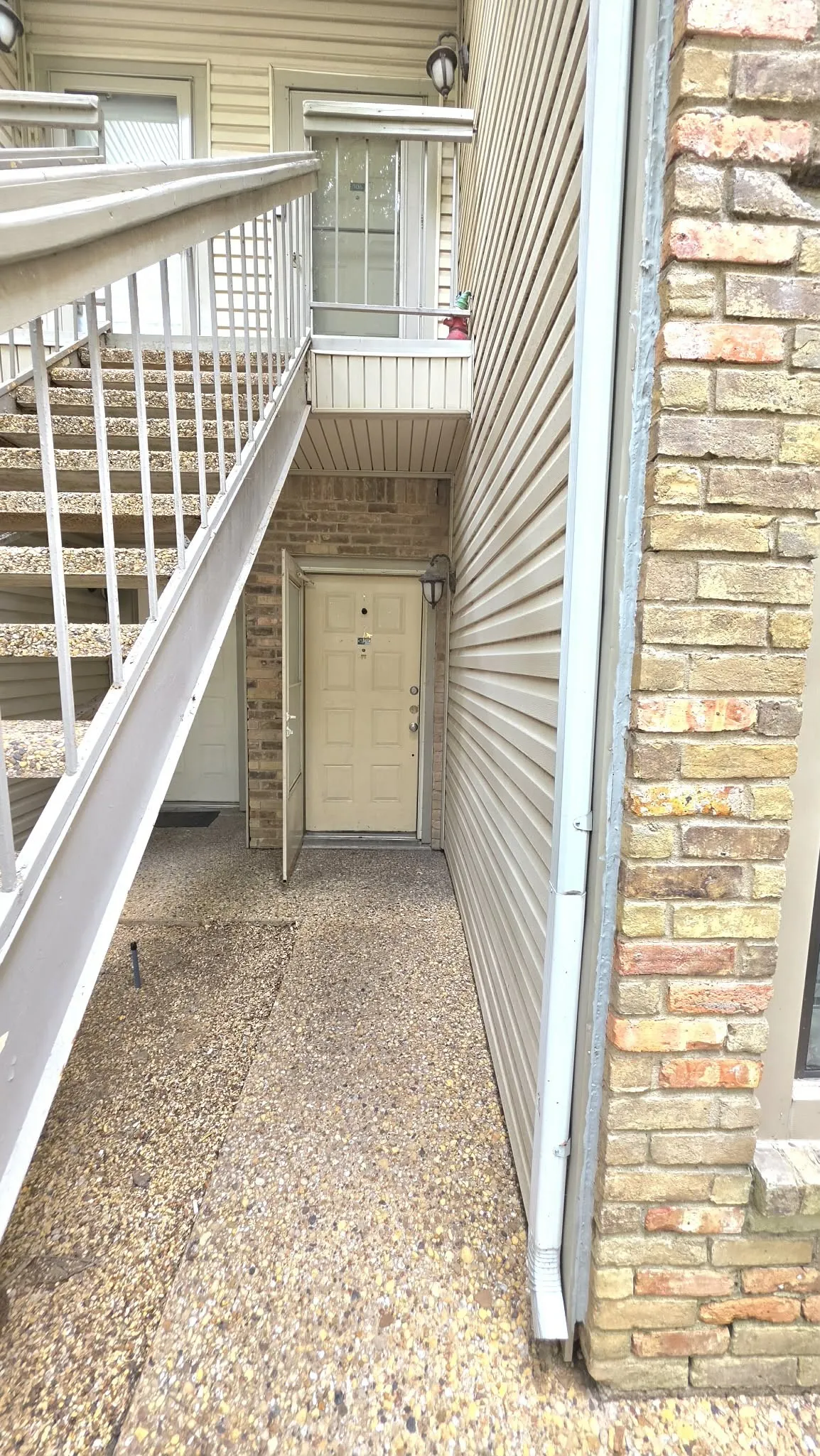 Brick and siding exterior with concrete stairs and exposed aggregate pathway