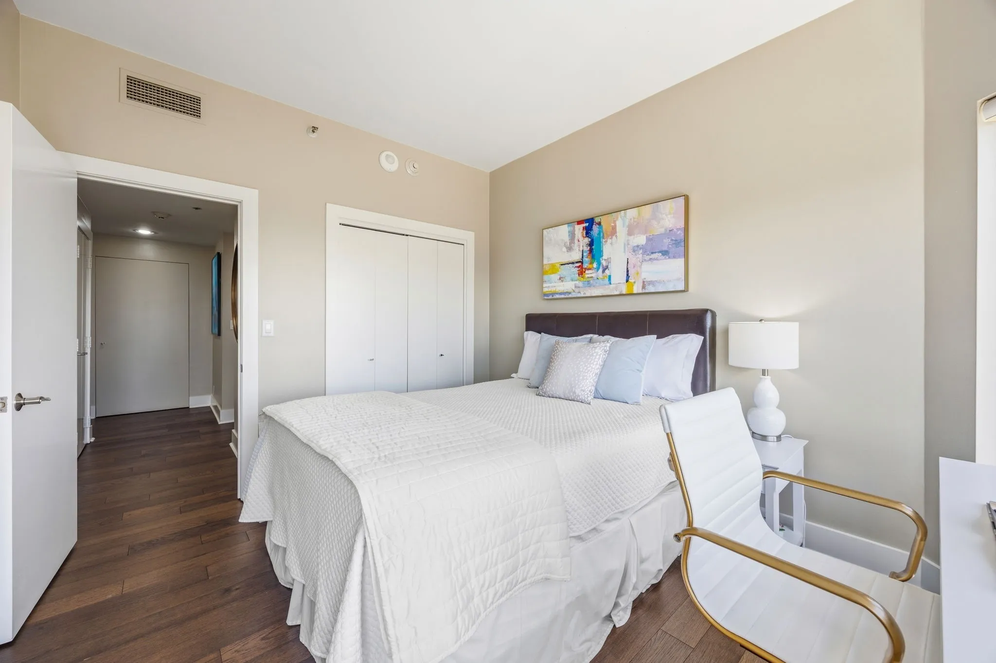Engineered wood flooring continues throughout the guest bedroom, adding warmth and a chic, polished touch to this inviting space.