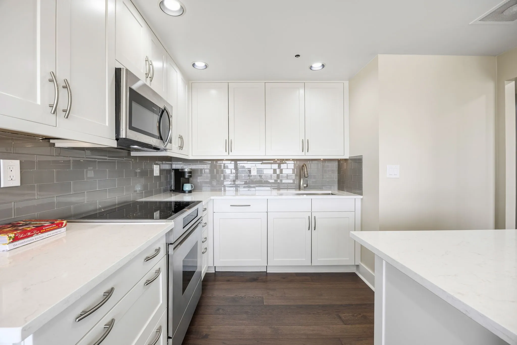 This view showcases the kitchen’s beautiful decorative glass tile backsplash and spacious breakfast bar, which opens seamlessly to the dining area—perfect for casual meals and entertaining.
