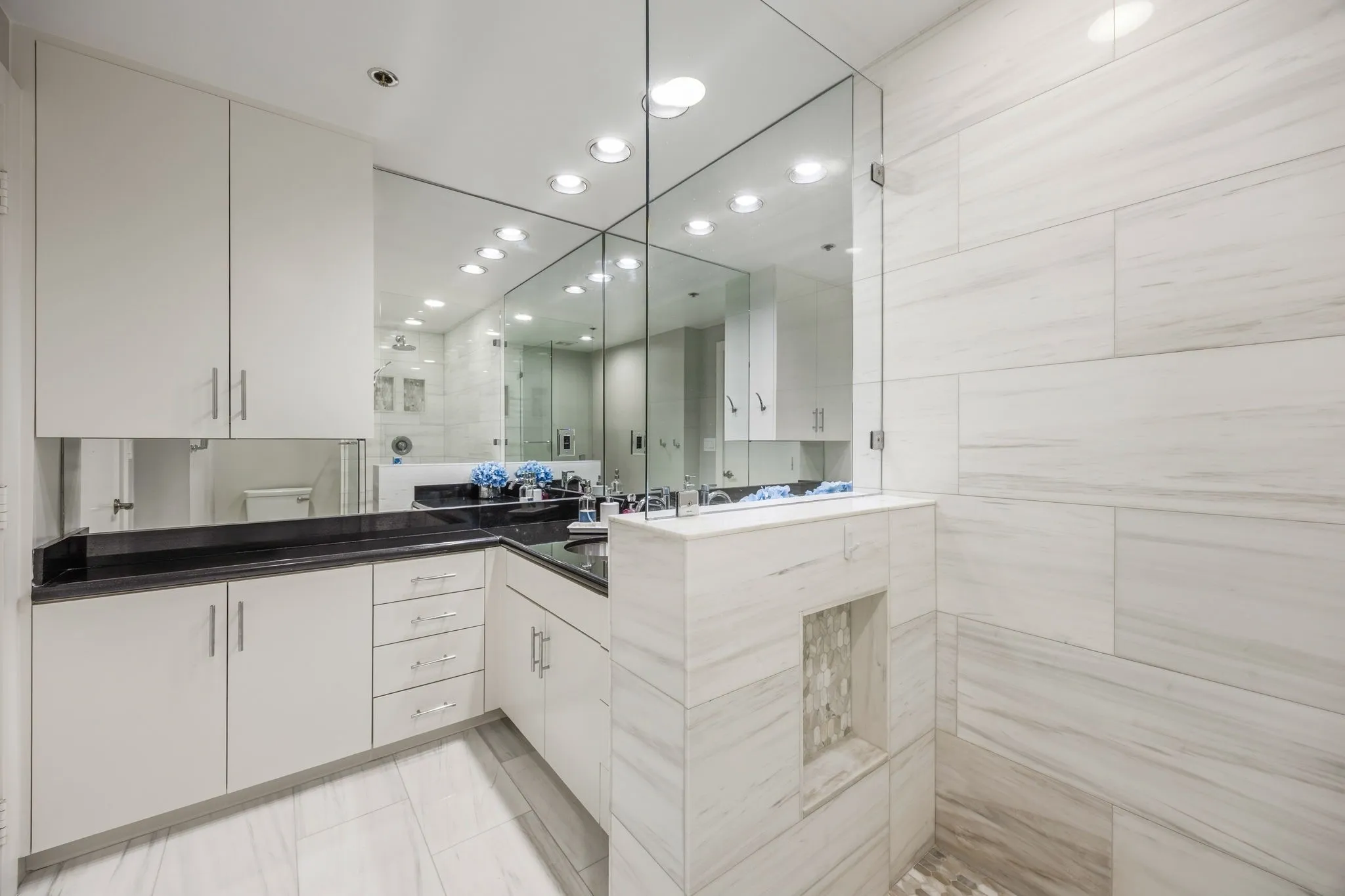 Abundant cabinetry in the primary bathroom provides plenty of storage for all your everyday essentials, while rich dark granite countertops create a striking contrast against the light and bright space.