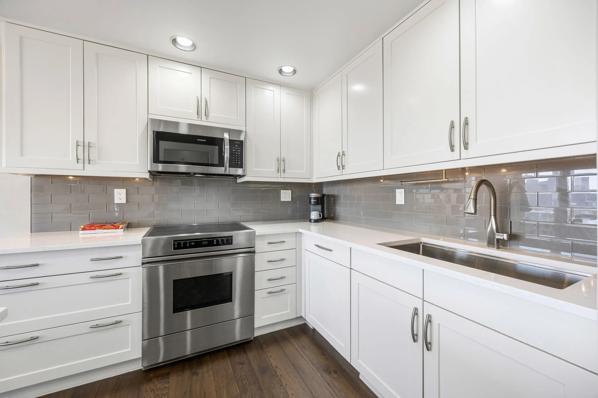 The kitchen features a large single-bowl sink, while convenient pot drawers beside the electric range provide ample storage for larger pots, pans, and cookware.