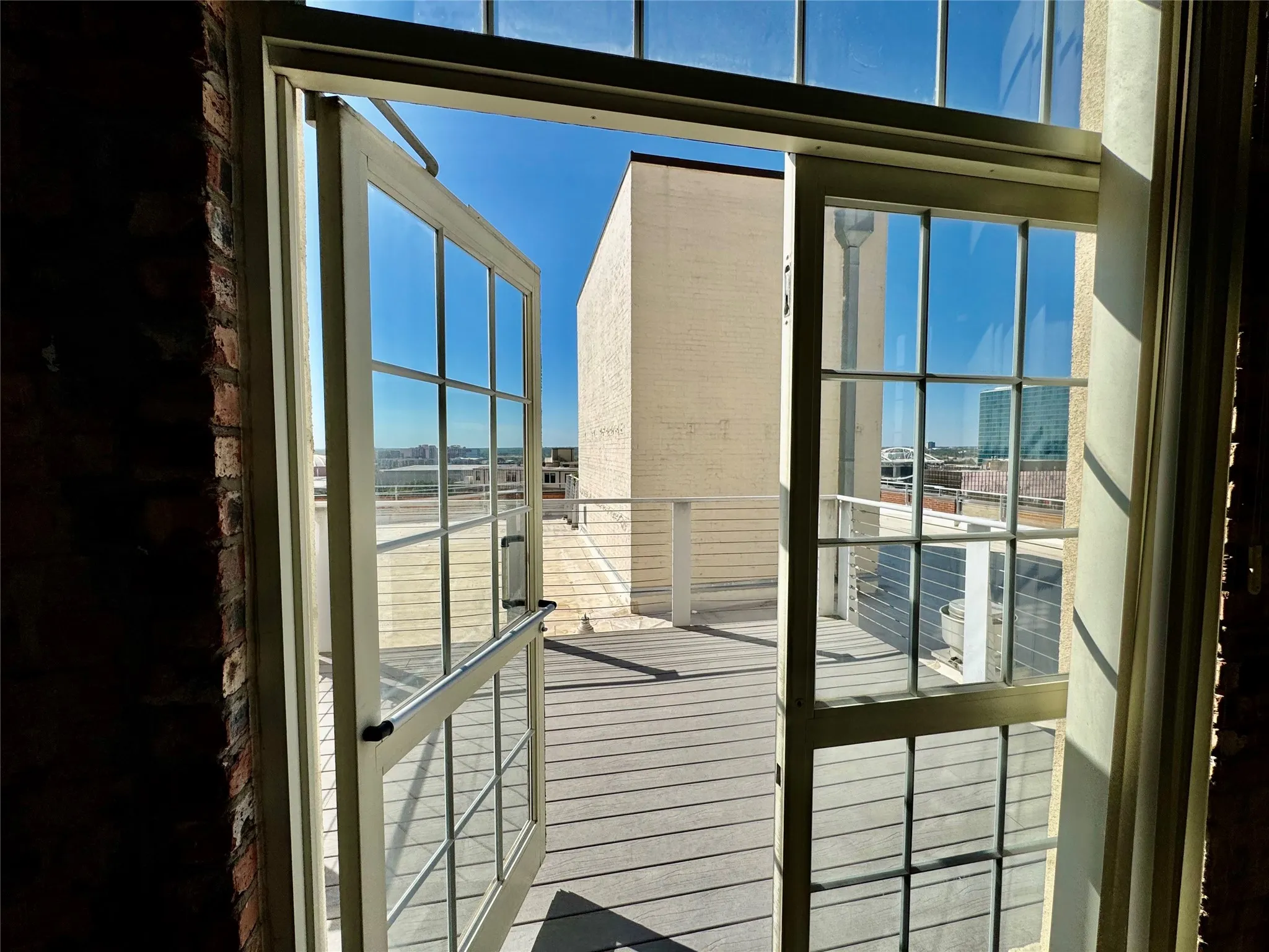 French doors with divided lites open to an expansive outdoor deck with cable railing and composite decking