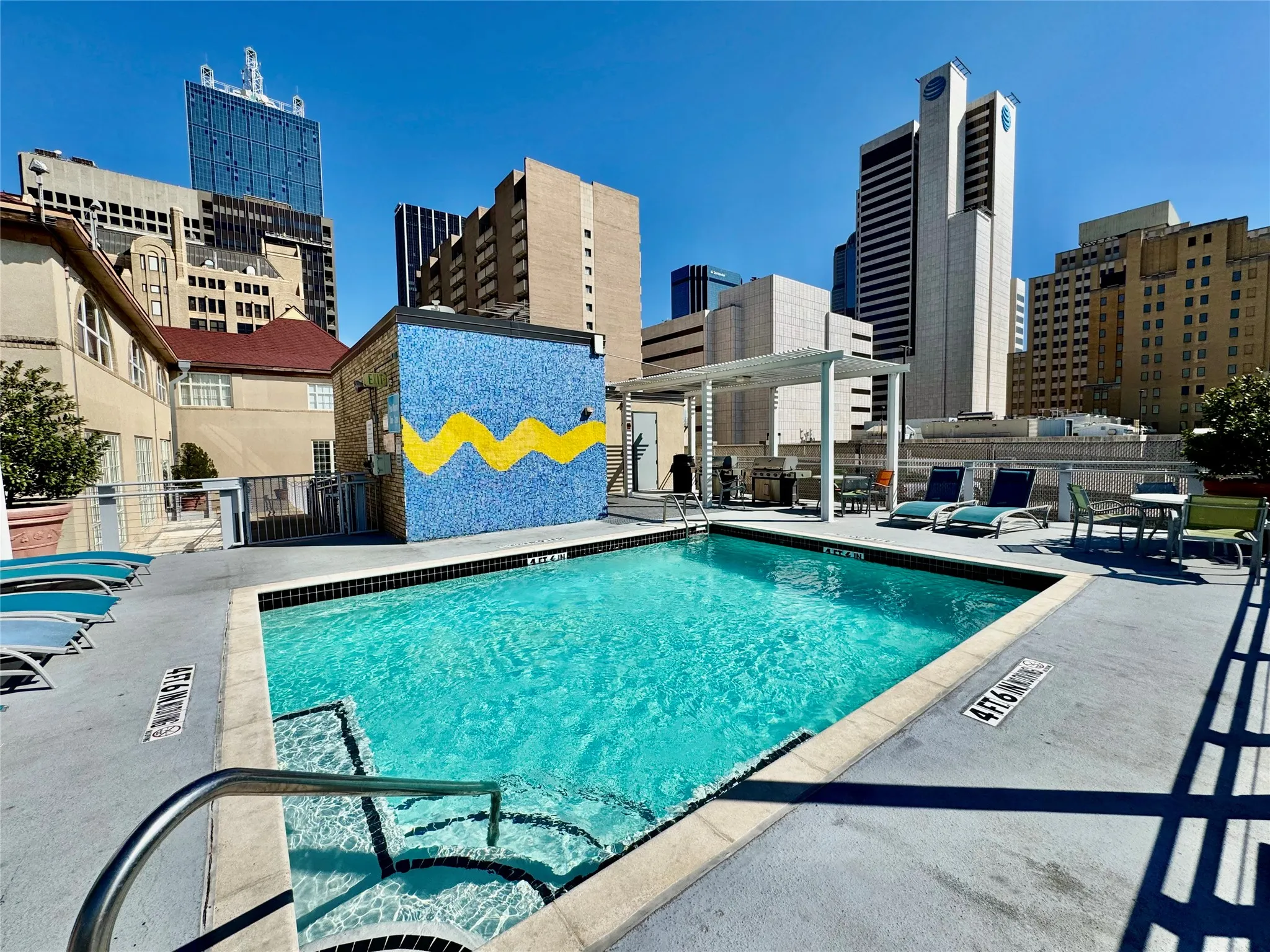 Rooftop swimming pool with integrated spa, concrete decking, and cityscape backdrop