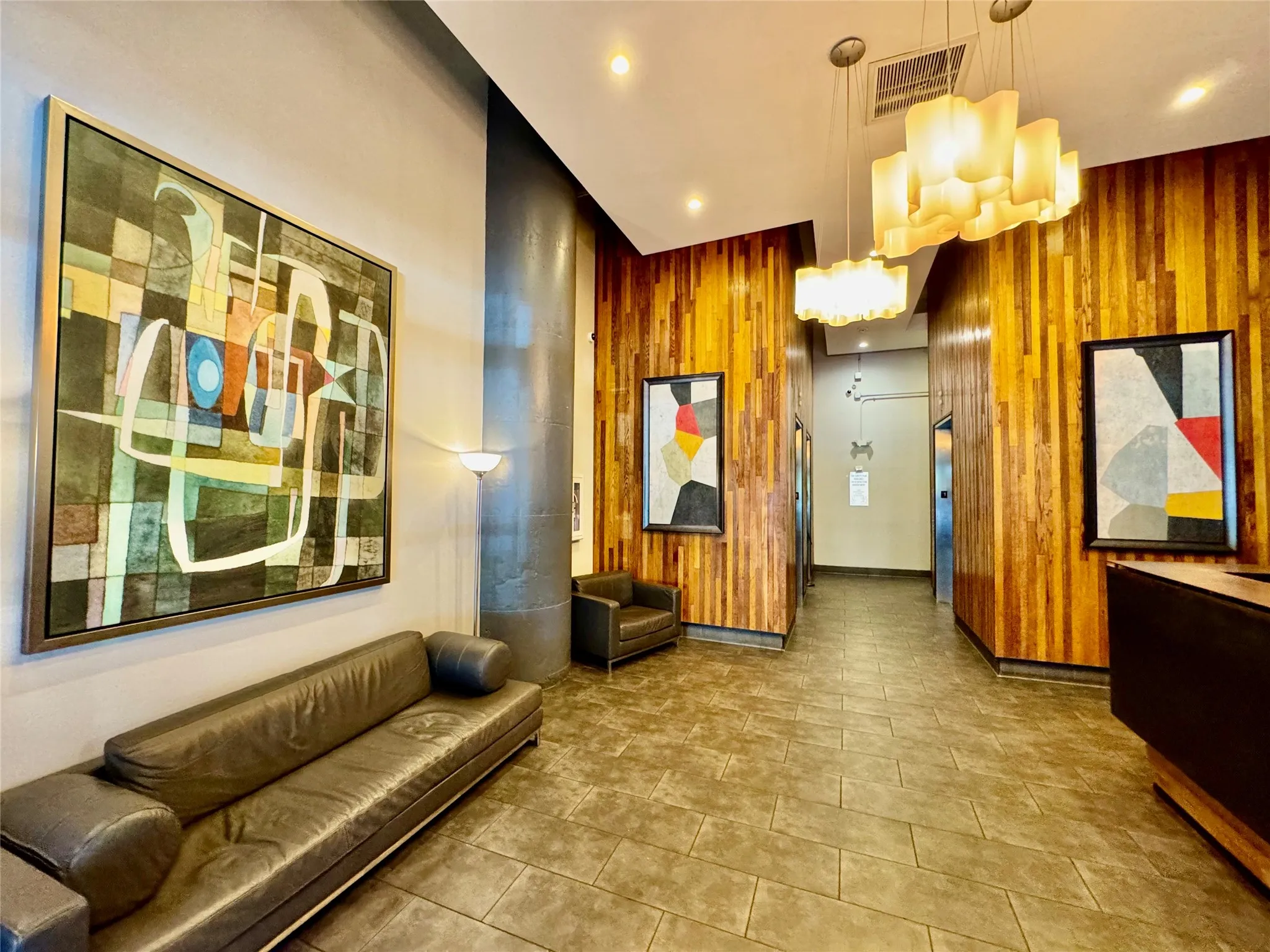 Textured wood-panel walls, modern chandelier lighting, and a neutral tile floor