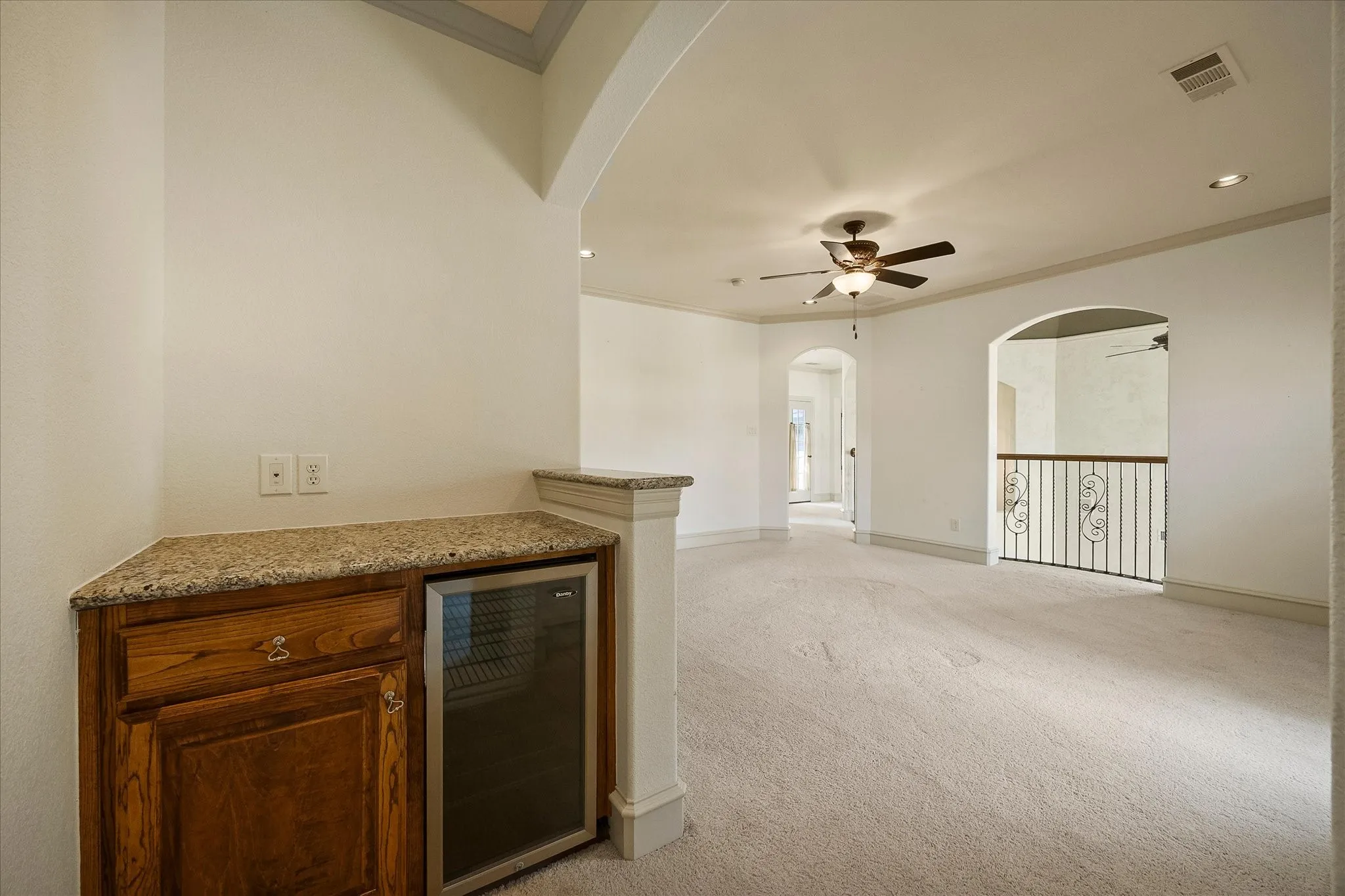 Built-in wet bar with wood cabinetry and granite-style countertop