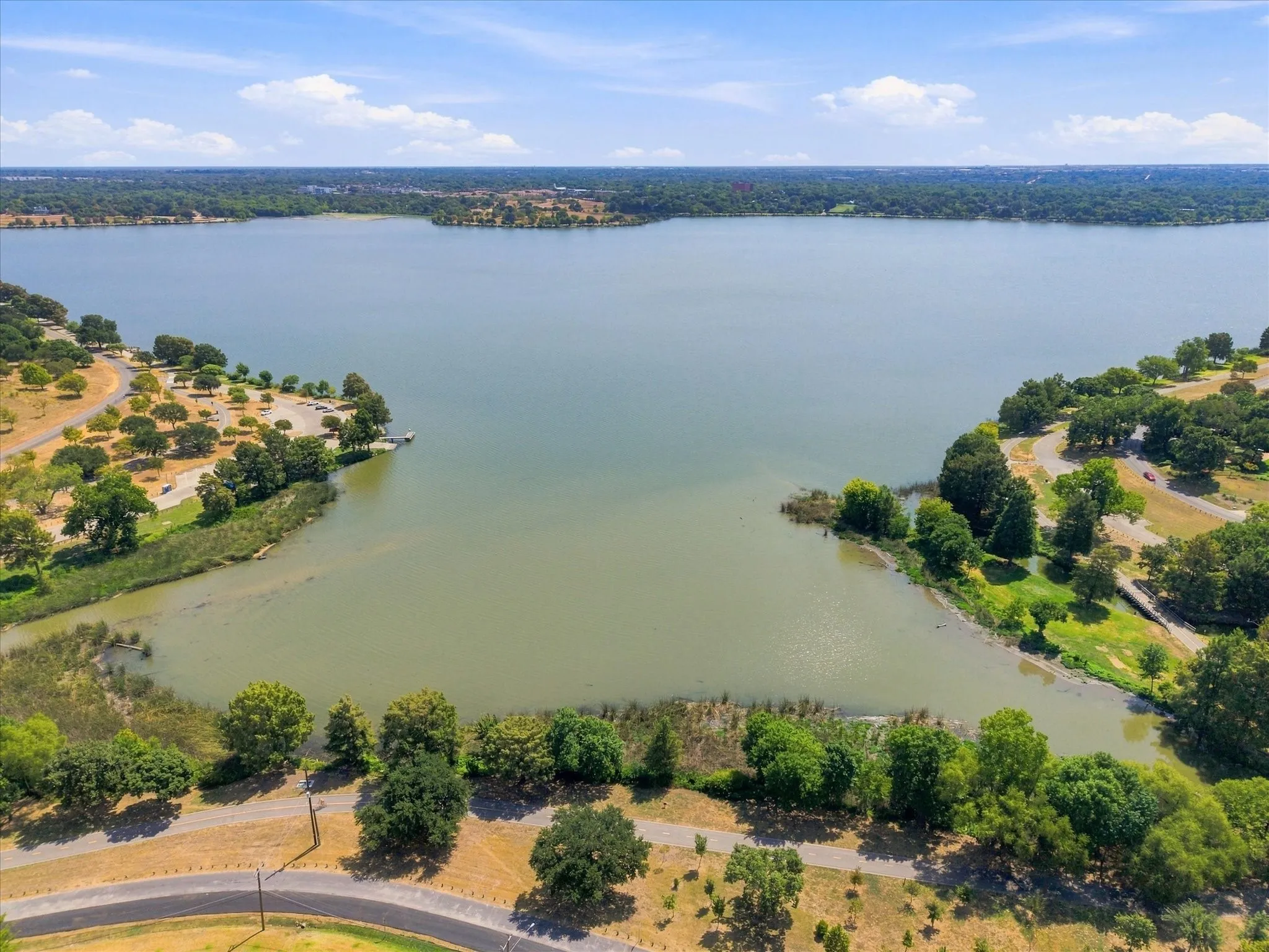 Expansive lake with surrounding natural landscaping and a partially visible boat dock