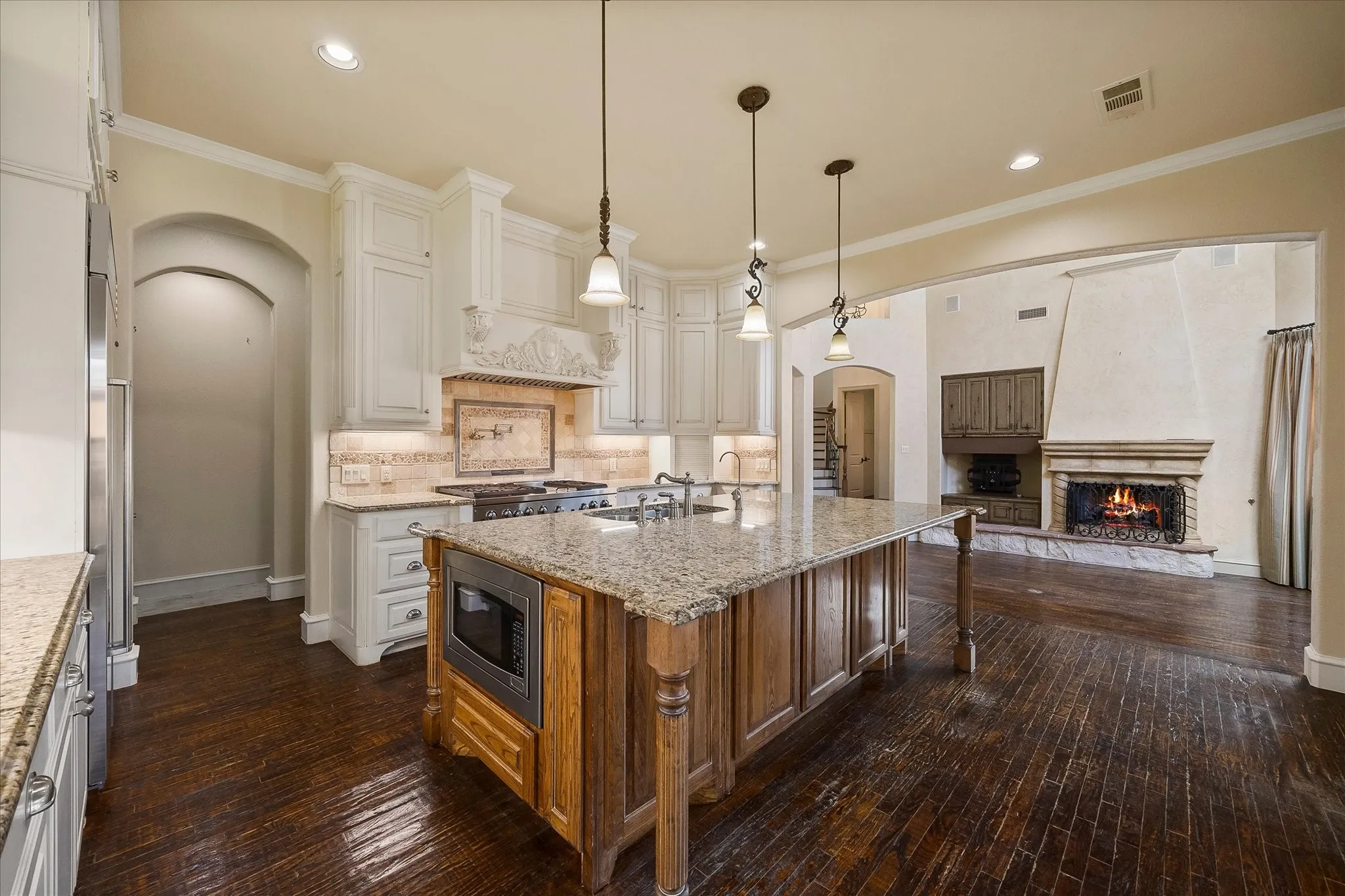 Gourmet kitchen with custom cabinetry, granite countertops, stainless steel appliances, and a central island with integrated microwave