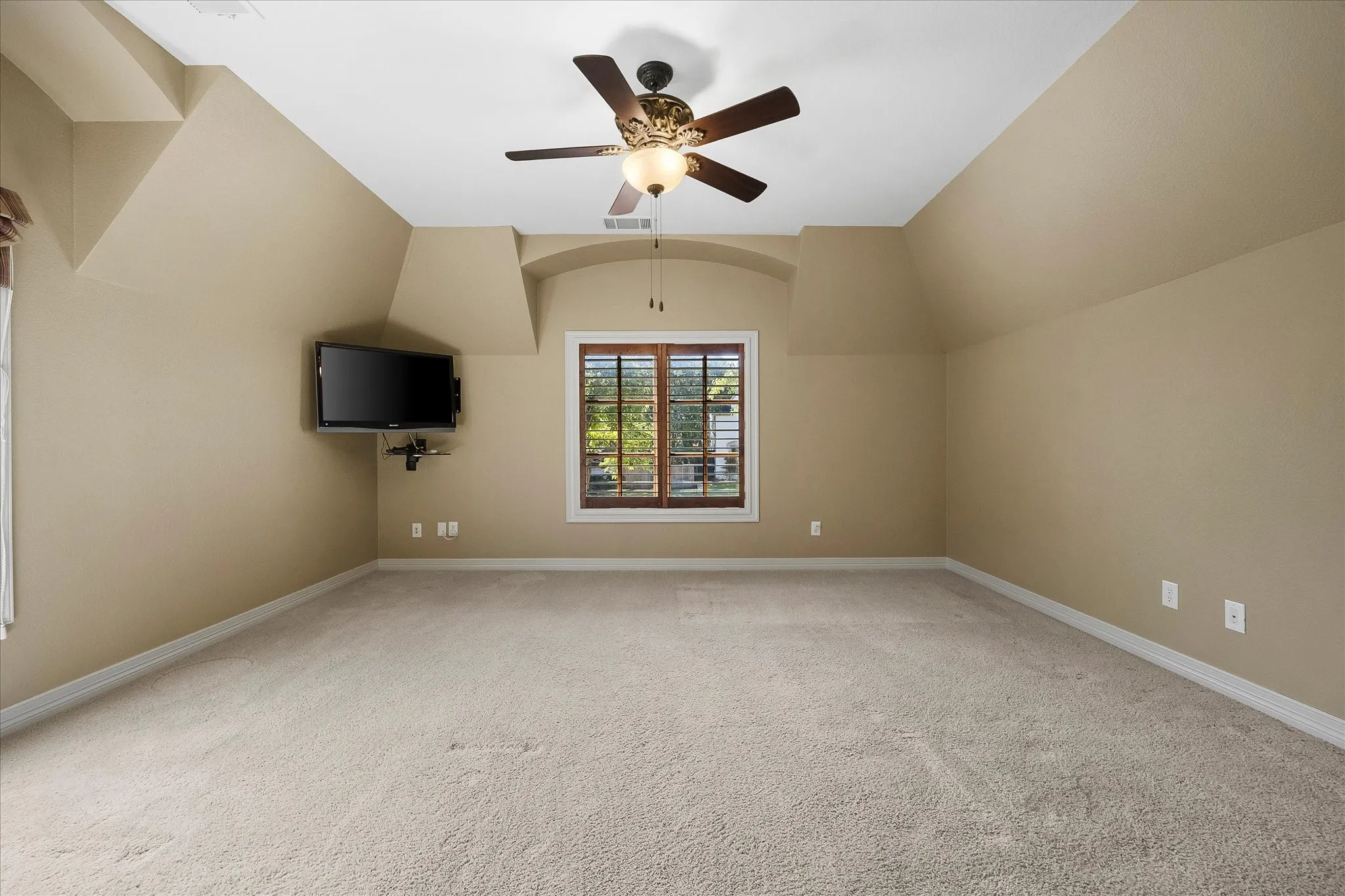 Sloped ceilings with a ceiling fan light fixture, light neutral carpet, and a window with wood blinds