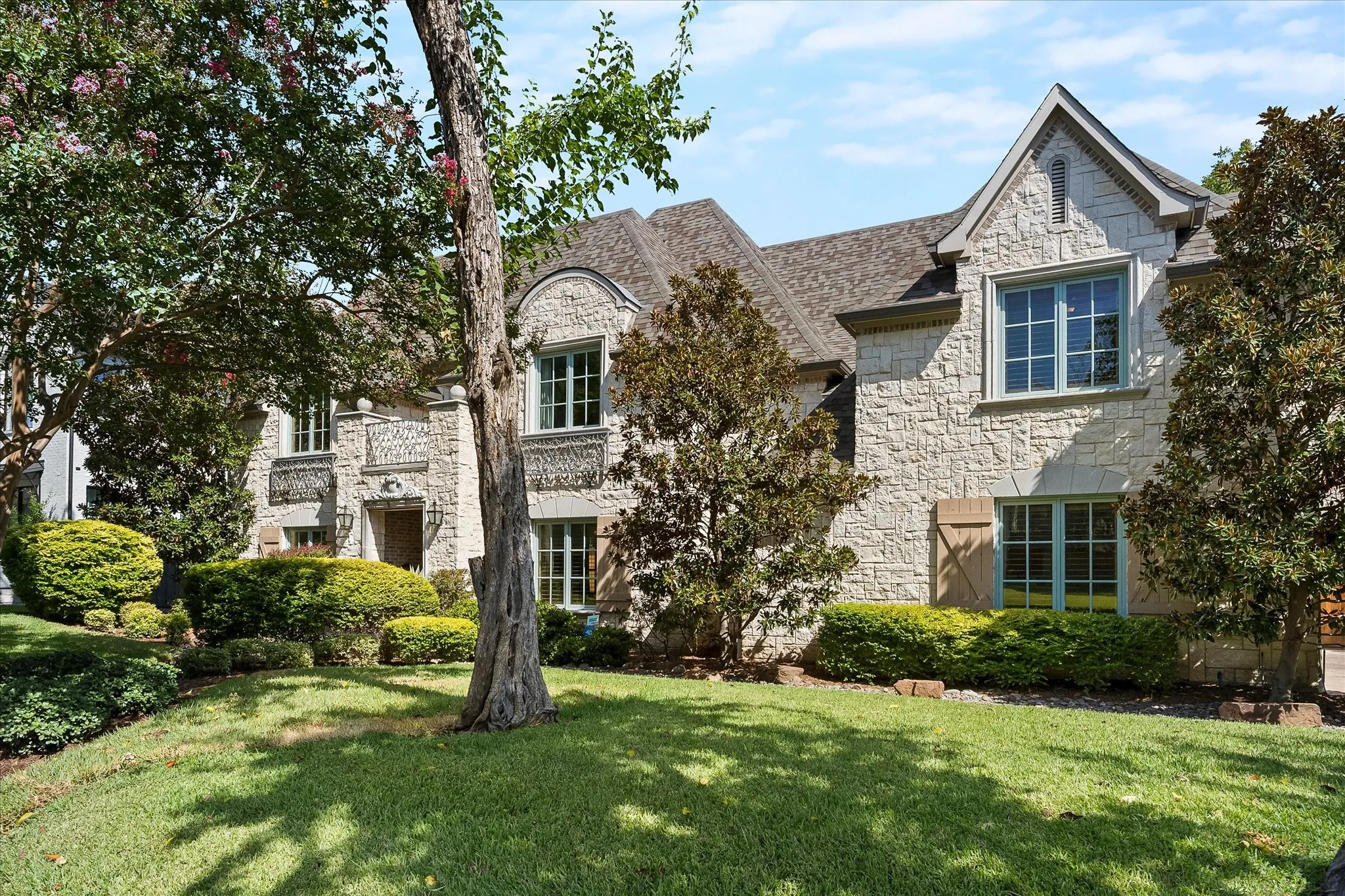 Stone facade residence with a pitched shingle roof
