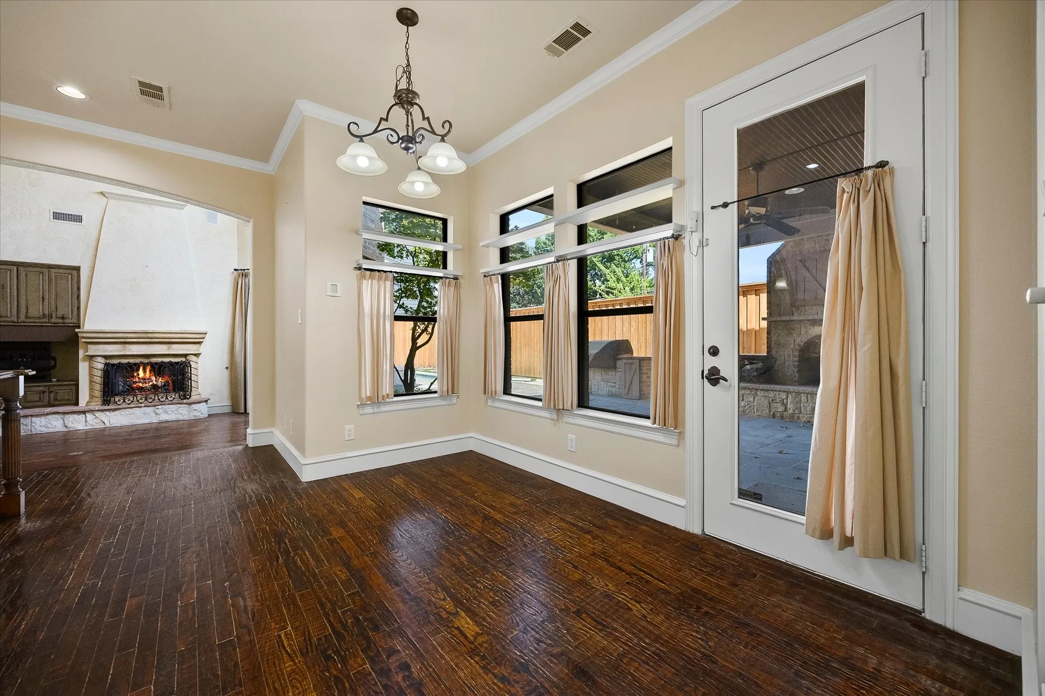 Hardwood-finish flooring, recessed lighting, and a chandelier illuminate this interior space
