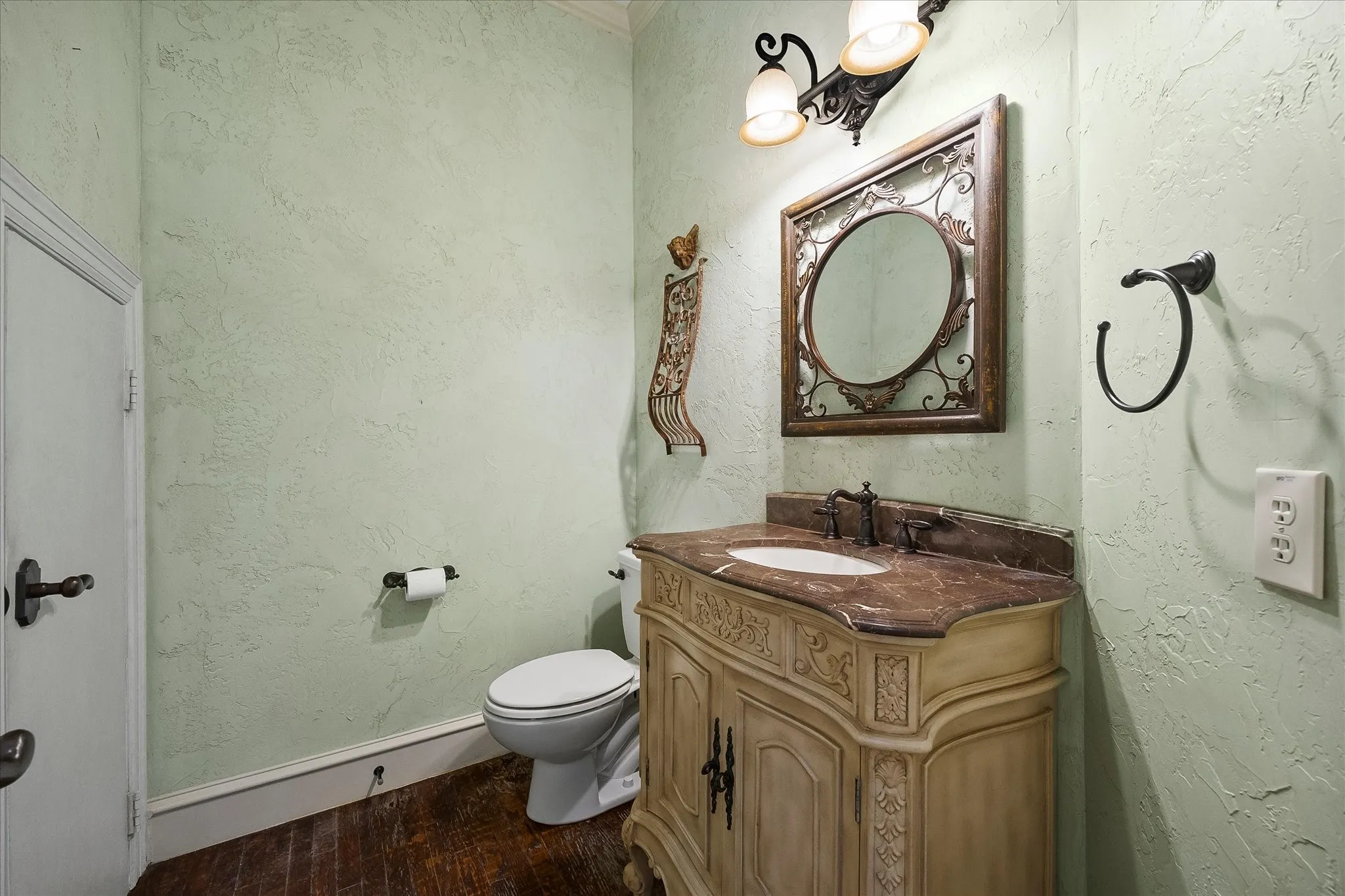 Decorative vanity with a marble countertop and undermount sink, complemented by a large ornate mirror