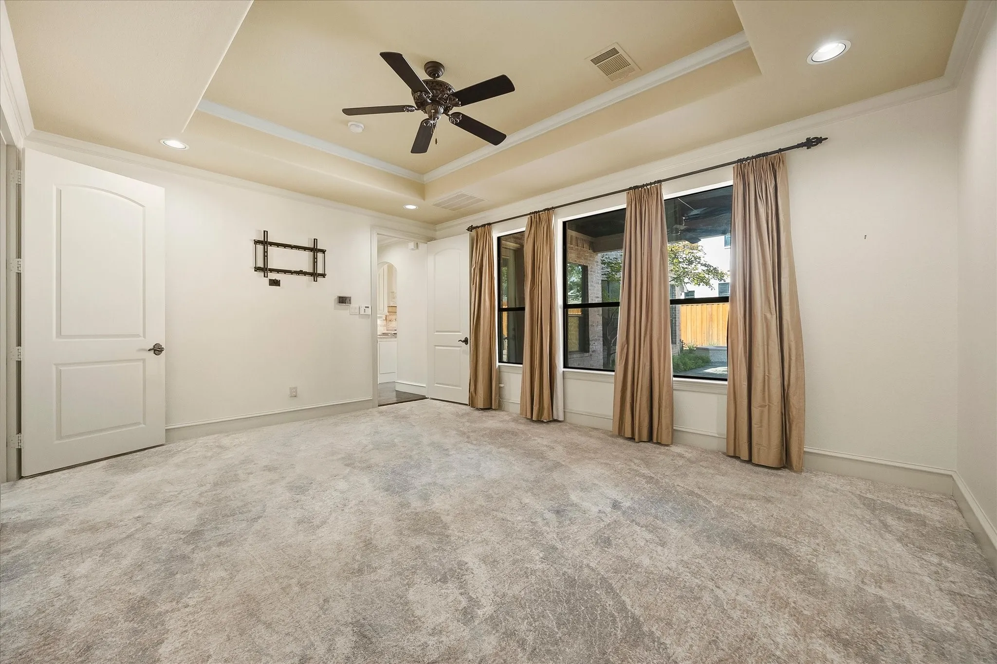 Tray ceiling with recessed lighting, dark-toned ceiling fan, light-toned carpeting, white trim, and multiple windows