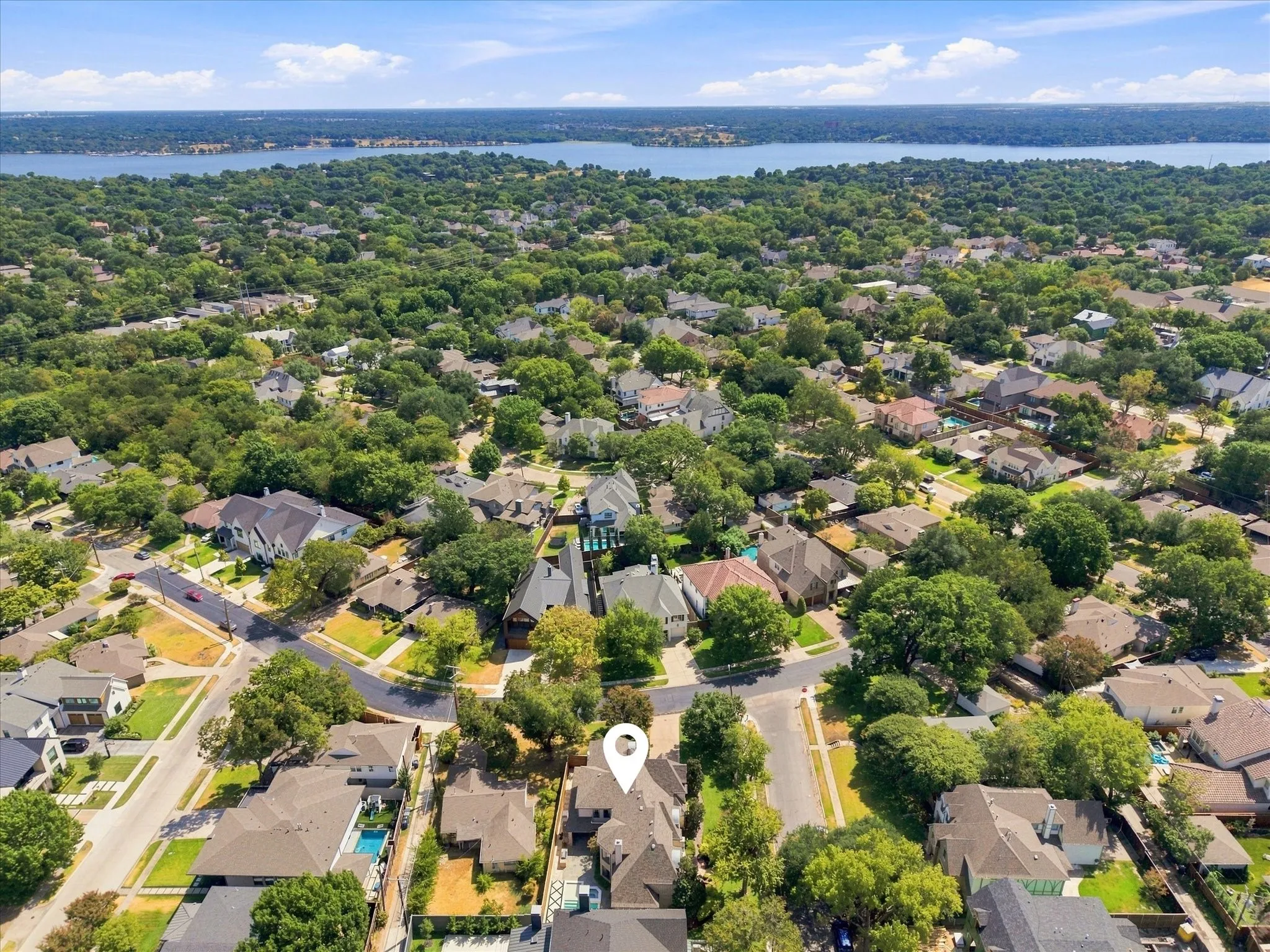 Aerial neighborhood perspective with abundant mature trees and distant water